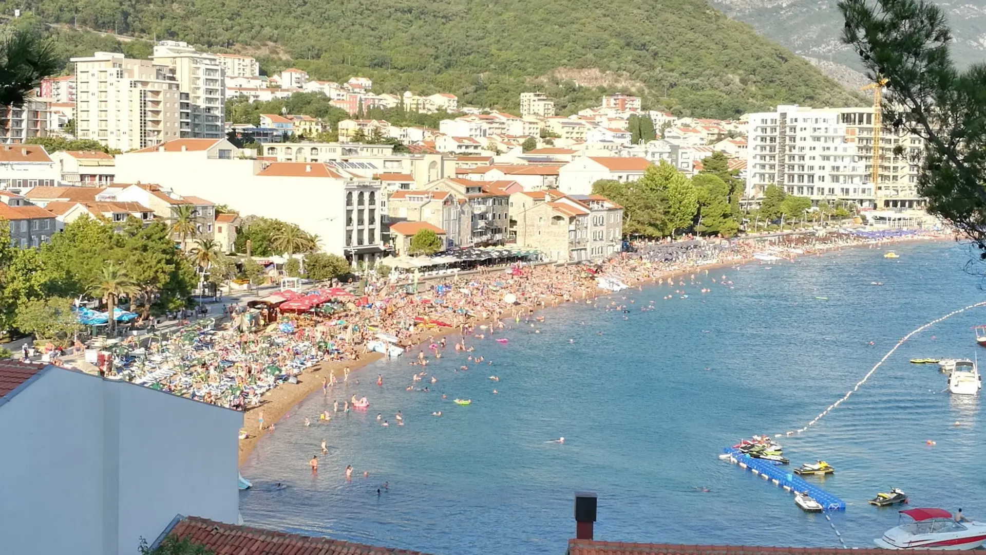 Petrovac's curved town beach and waterfront buildings in bright daylight