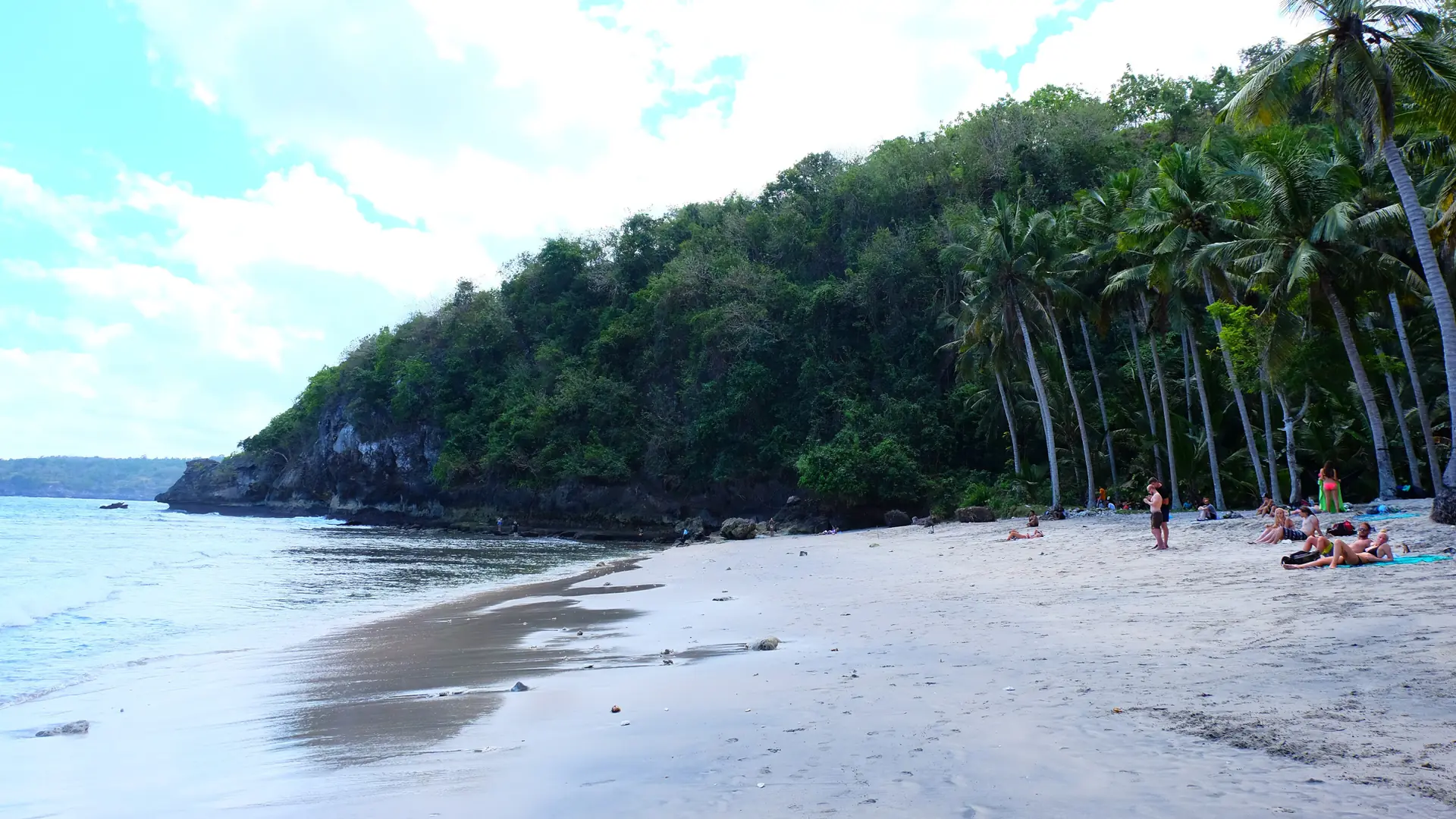Palms and visitors beside Crystal Bay beach on the wider Nusa Penida coast