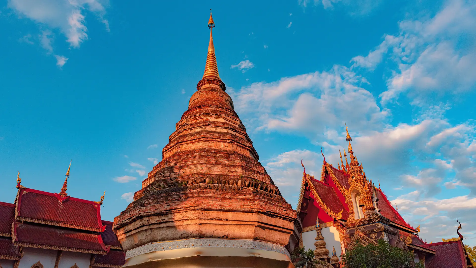 Ornate red and gold Buddhist temple beneath a blue Chiang Mai sky