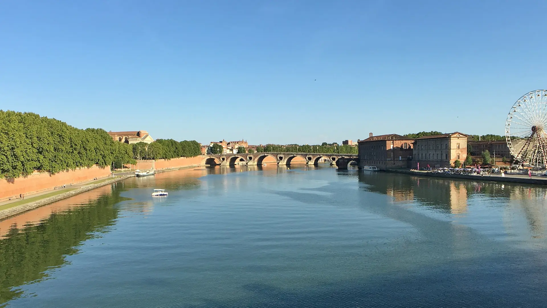 Pont Neuf spanning the Garonne between Toulouse’s tree-lined brick quays on a sunny day