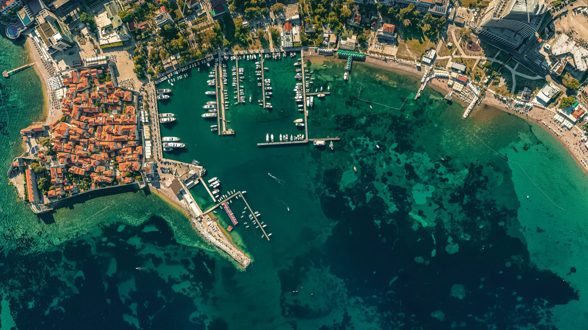 Budva Old Town beside a marina filled with boats and clear Adriatic water