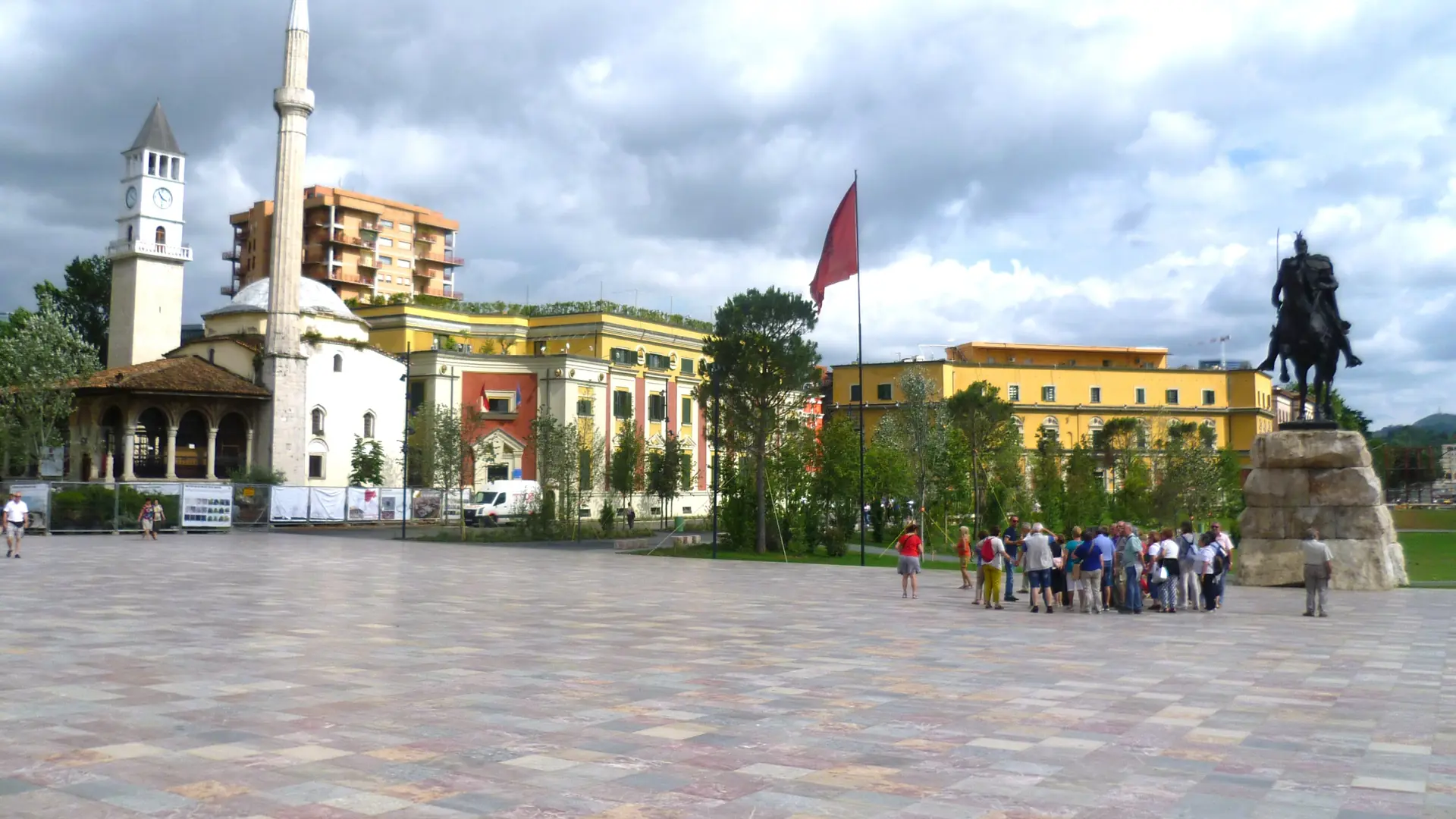 Skanderbeg Square in Tirana on a sunny day: the Et'hem Bey Mosque, the clock tower and the equestrian statue beyond the square's multicoloured stone paving