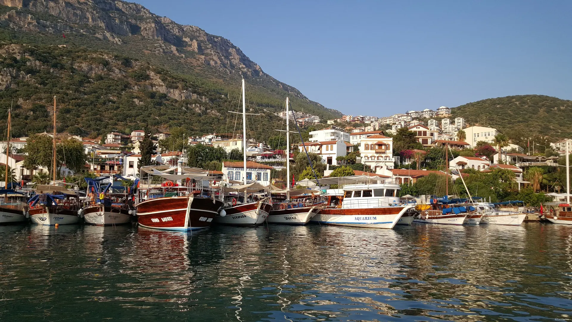 Fishing boats moored in Kaş harbour below white hillside homes