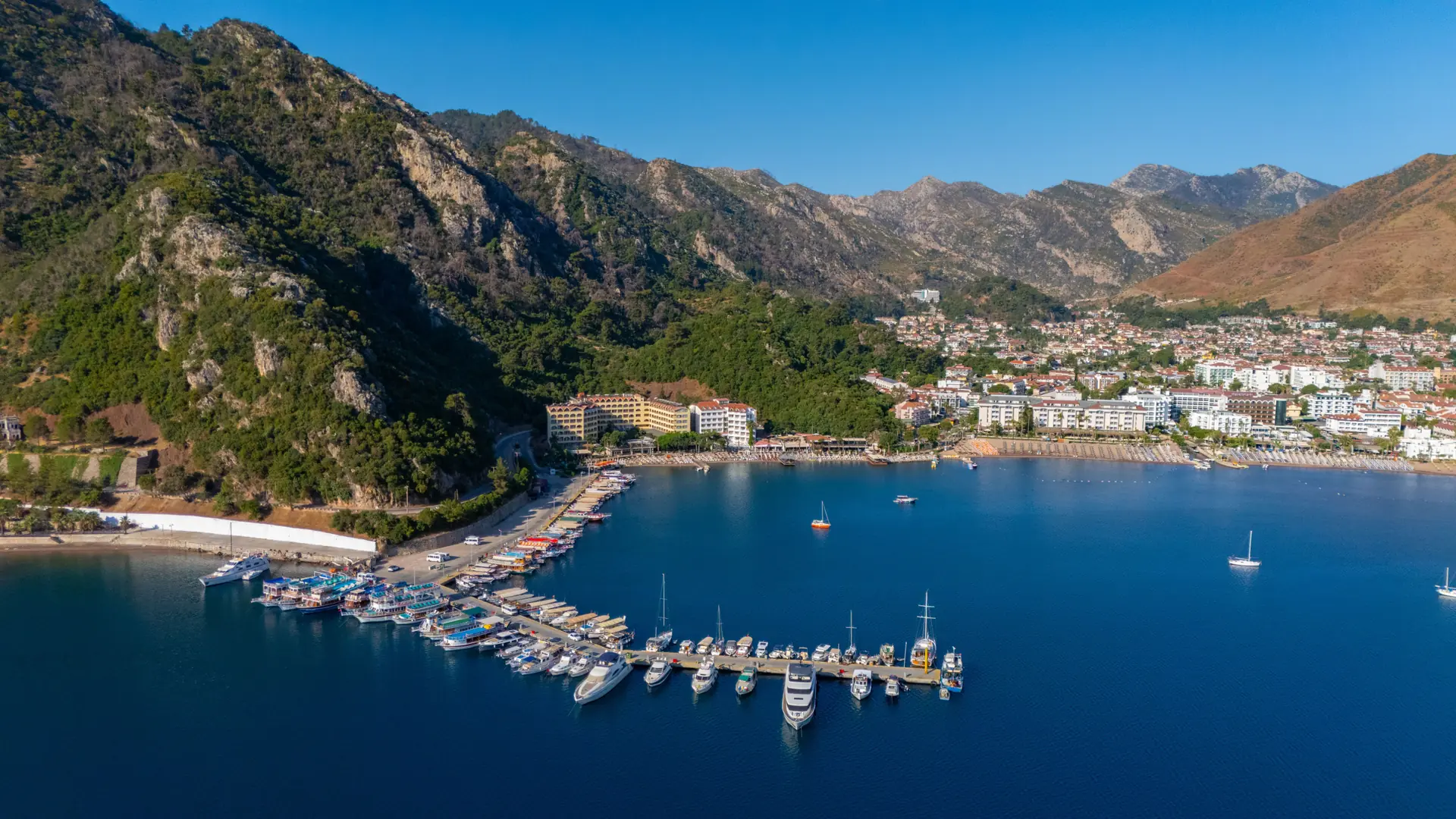 Sunny Marmaris marina and castle quarter wrapped by green hills and vivid blue water