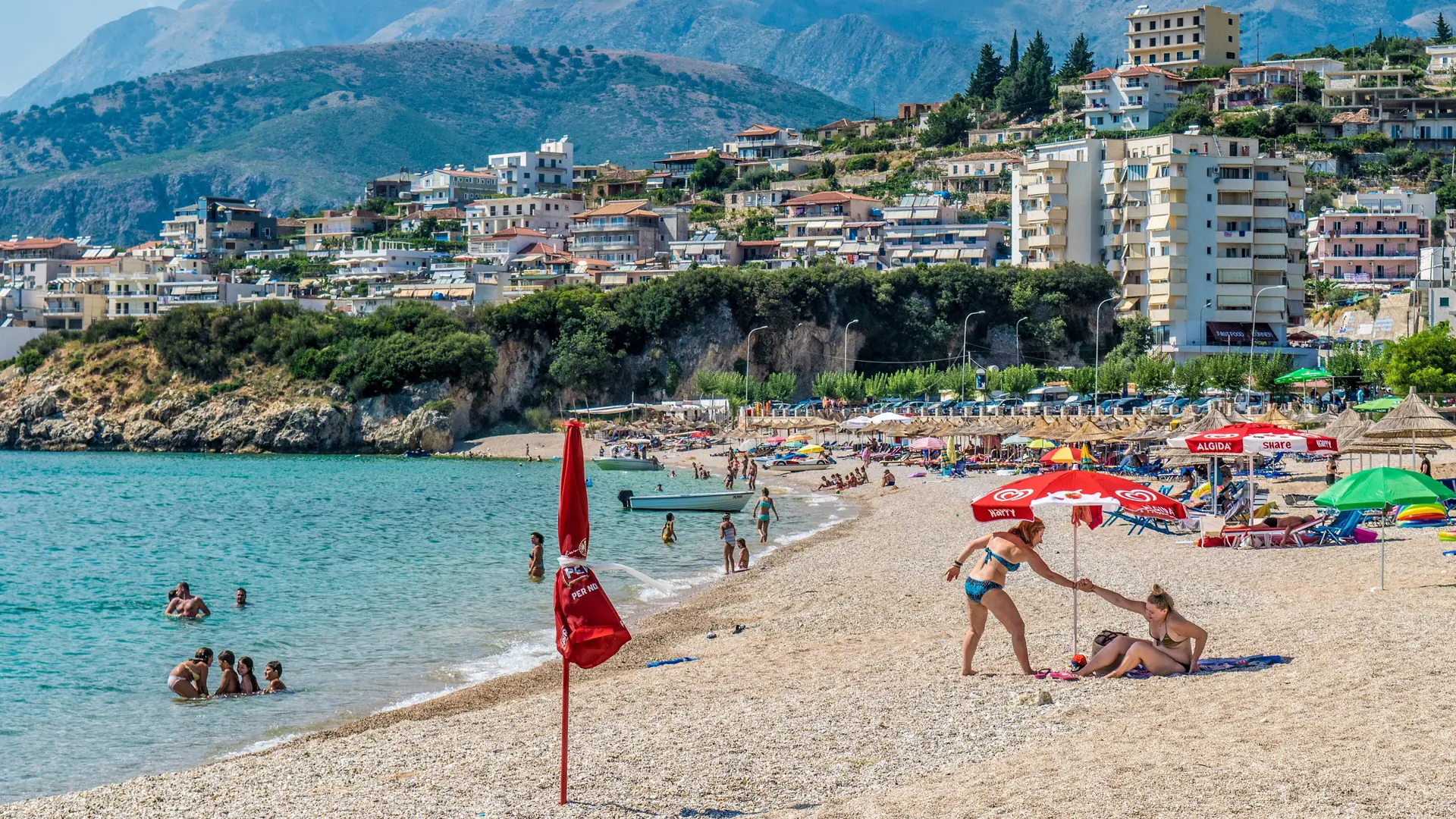 Calm turquoise water and umbrellas at Potam beach on the south side of Himarë bay