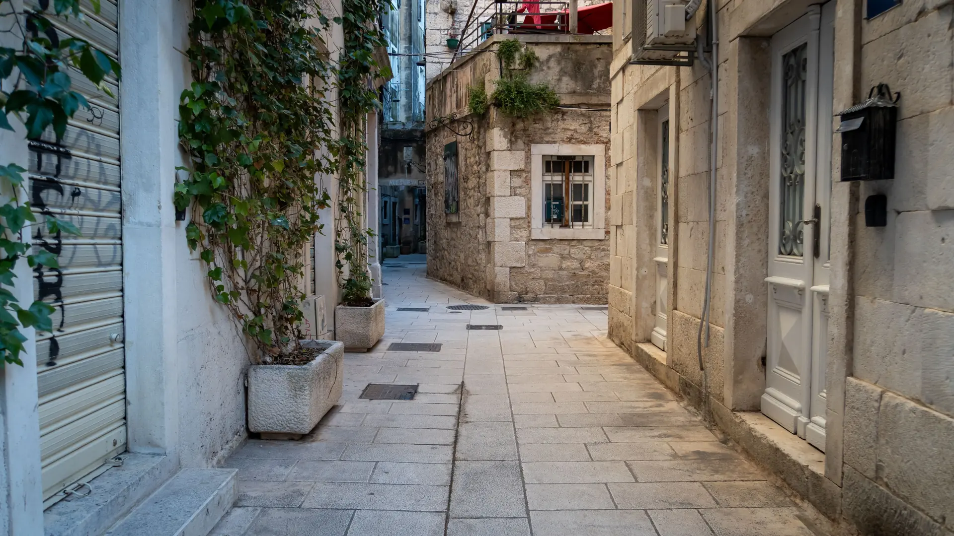 An ivy-shaded stone lane between old houses in Split's Veli Varoš