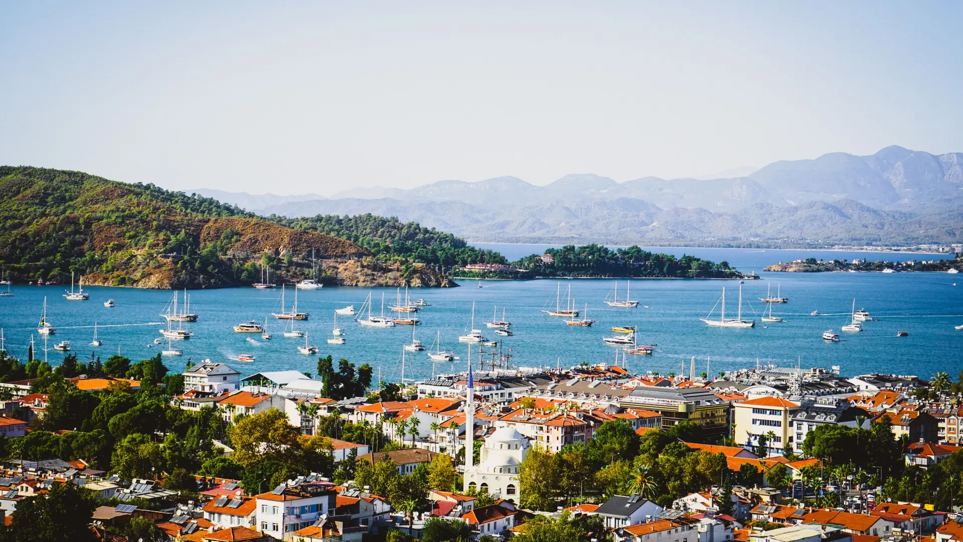 Sailboats anchored across Fethiye Bay below green mountains