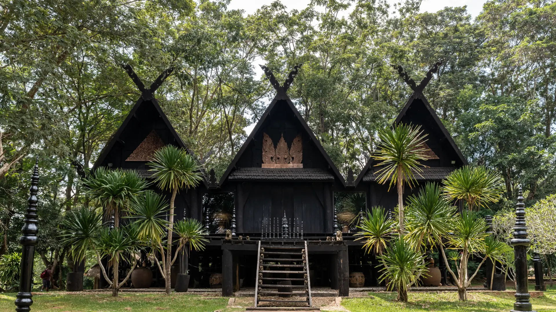 Black timber pavilions among trees at Baan Dam in Nang Lae
