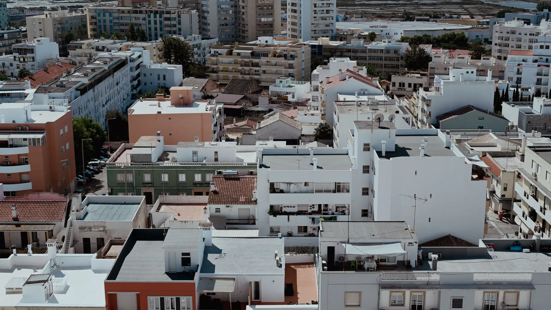 Aerial view over Faro's white and terracotta city roofs toward the coast