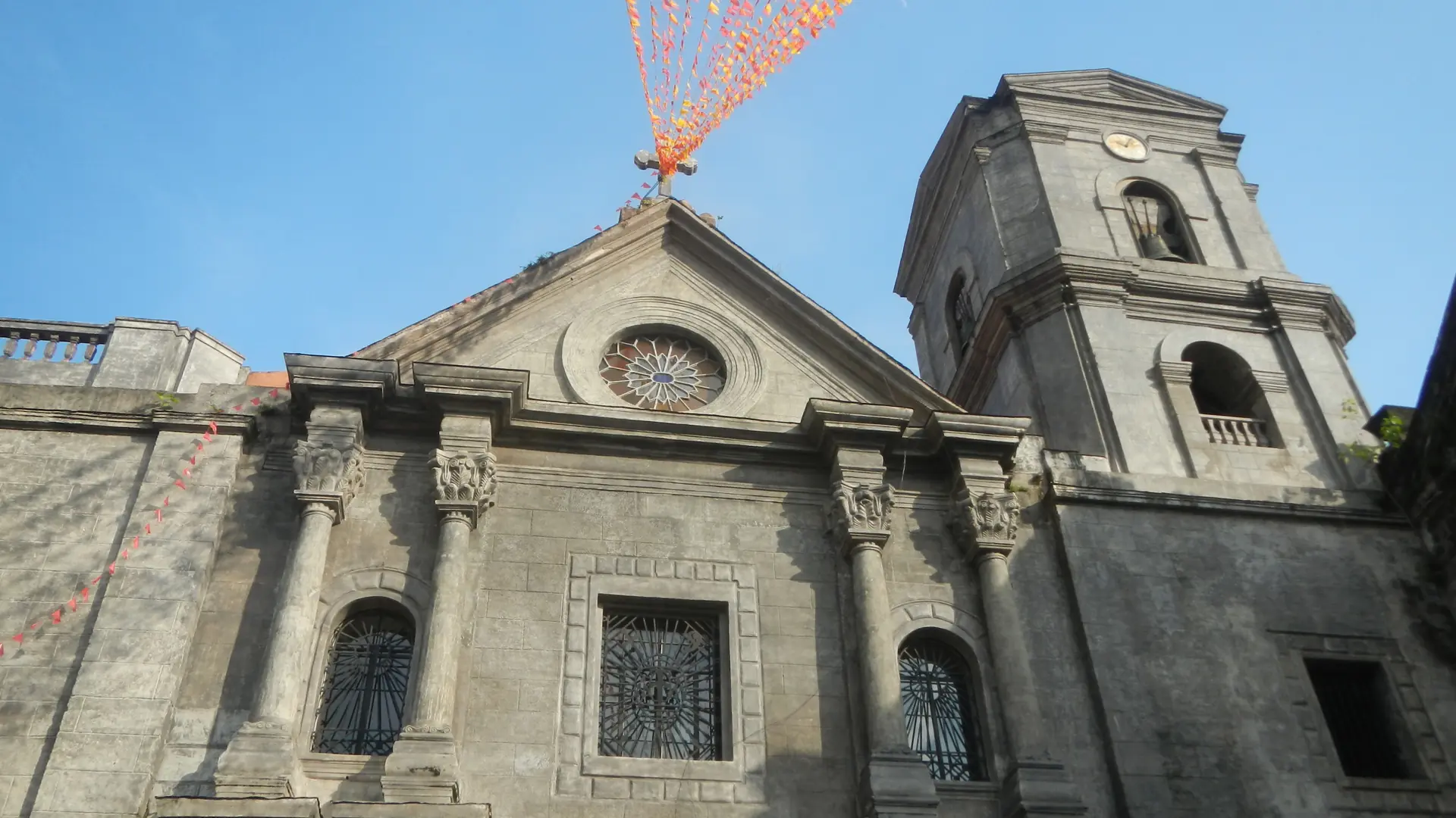 The stone facade and bell tower of San Agustin Church in Intramuros beneath a blue sky