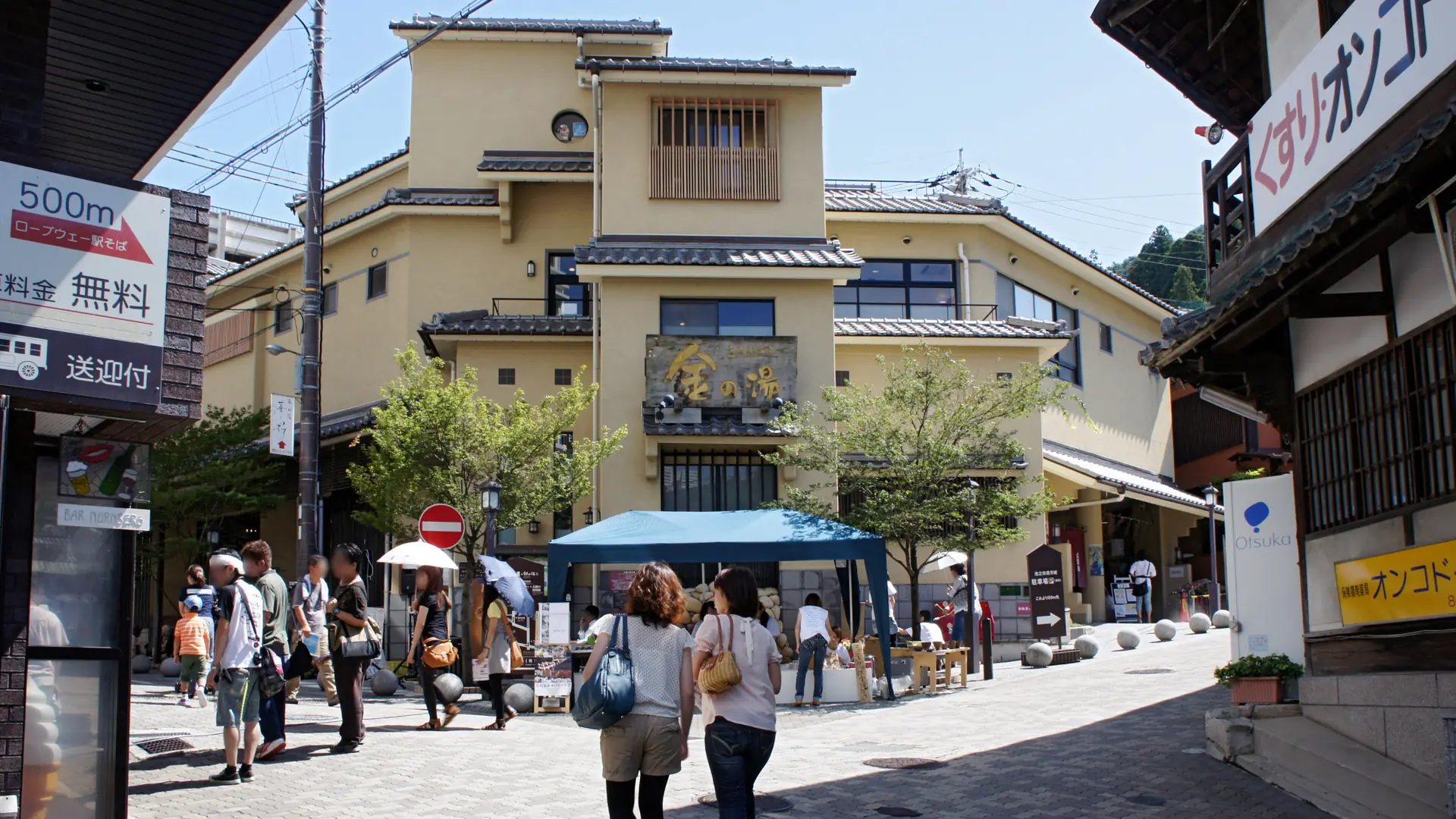 Kin no Yu’s yellow bathhouse facade and stone-paved Arima street in sunshine
