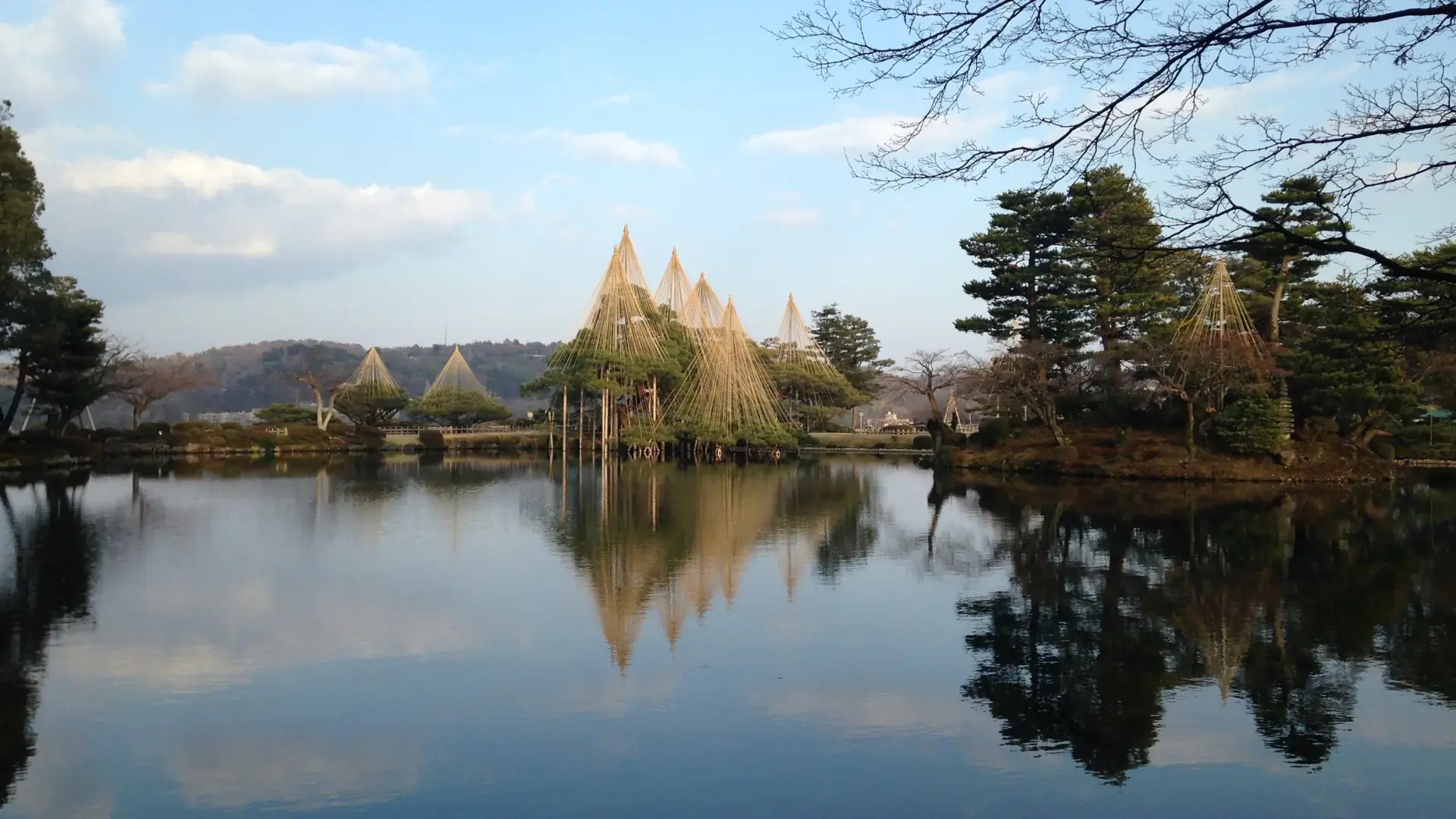 Kotoji lantern and reflective pond among Kenrokuen Garden's vivid green pines
