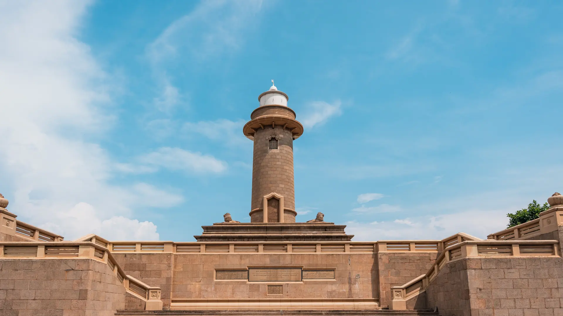 Colombo Lighthouse rising above stone walls under a bright blue sky