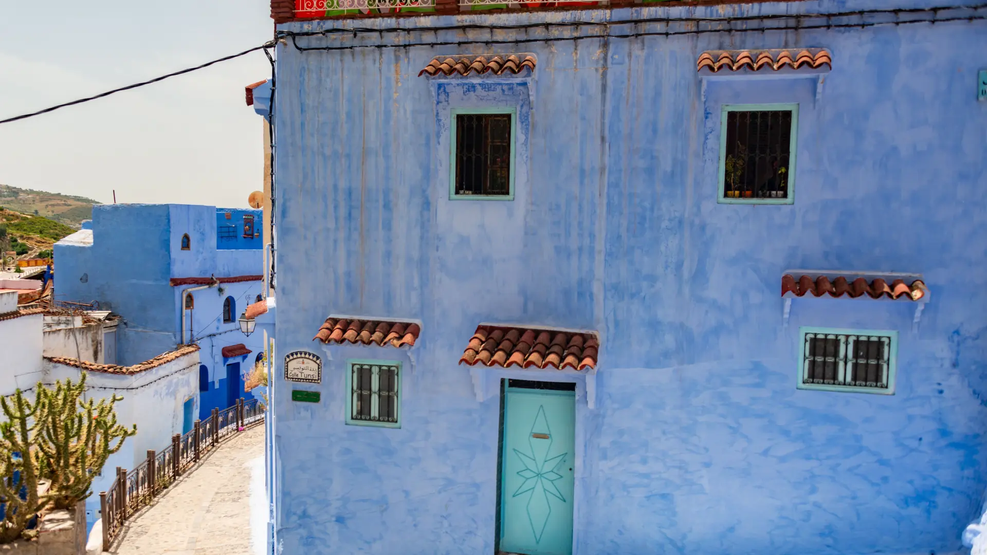 Blue-painted Chefchaouen medina facade with turquoise door in daylight