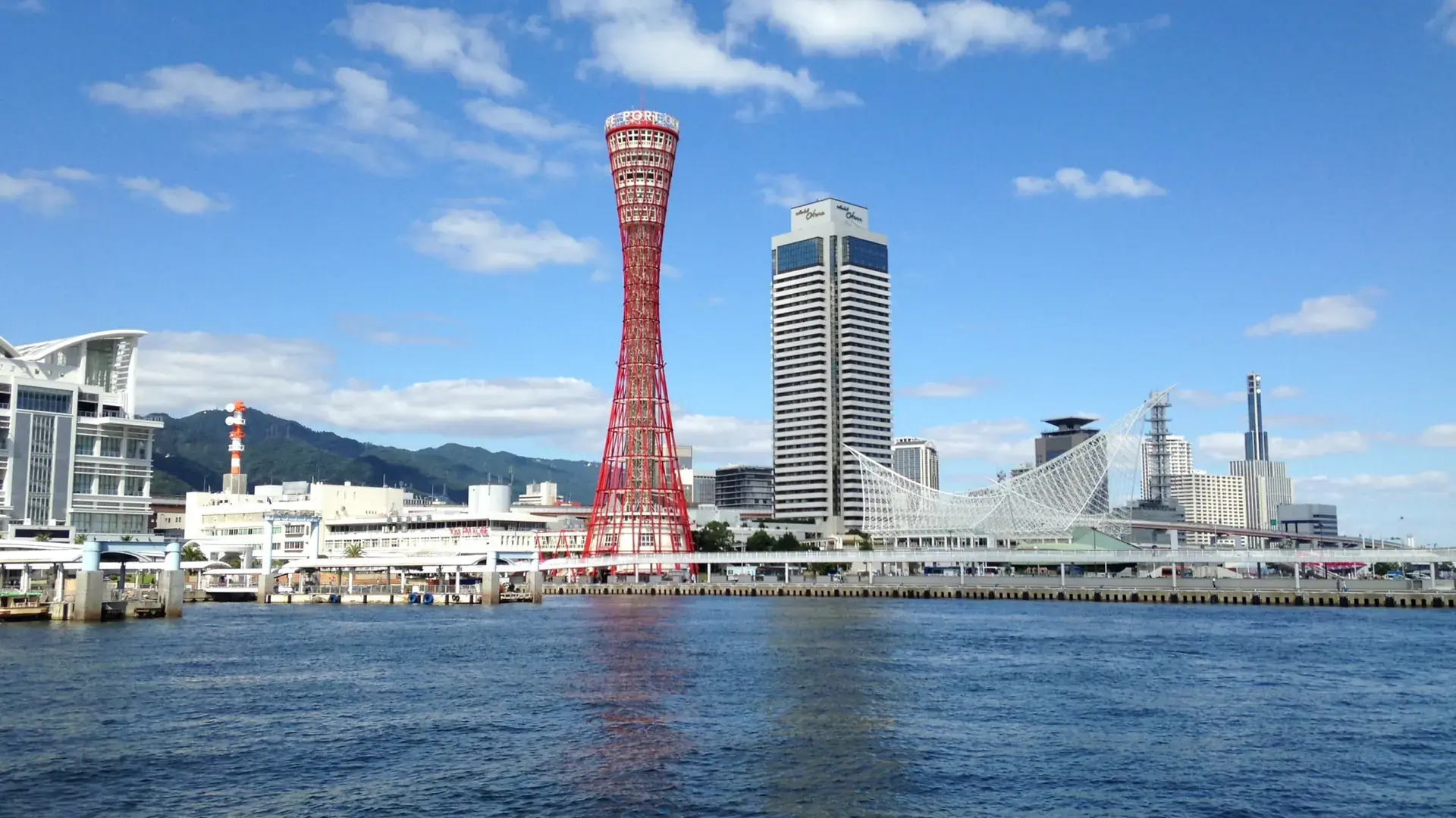 Kobe Harborland's red Port Tower, Ferris wheel and sparkling blue waterfront in sunshine