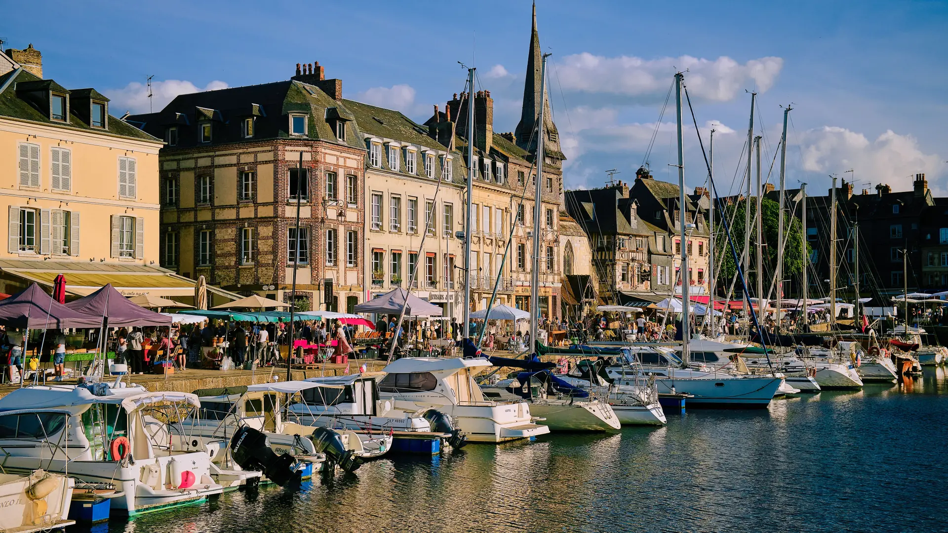 Boats and historic buildings beside the Vieux Bassin in Honfleur in daylight