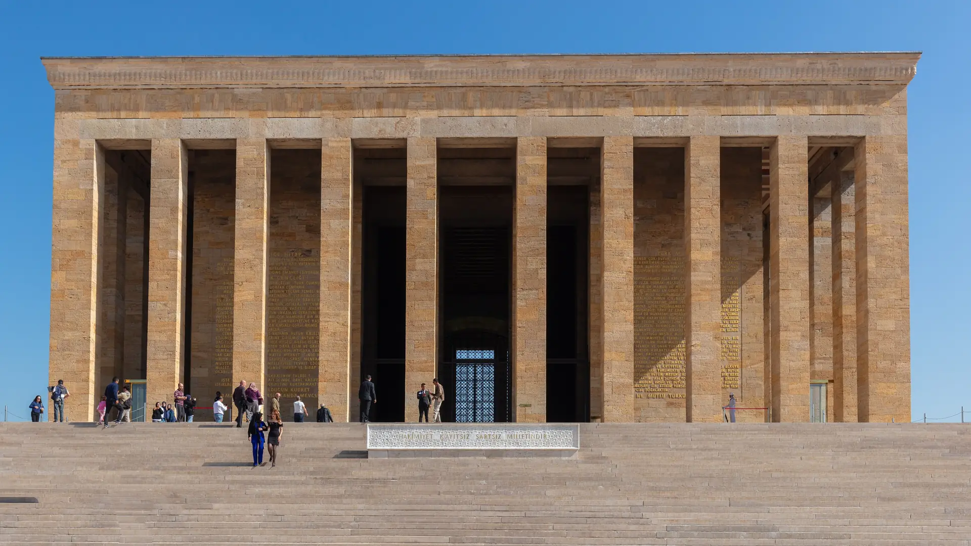 Sunlit stone colonnade and broad steps of Anıtkabir in Ankara under a blue sky