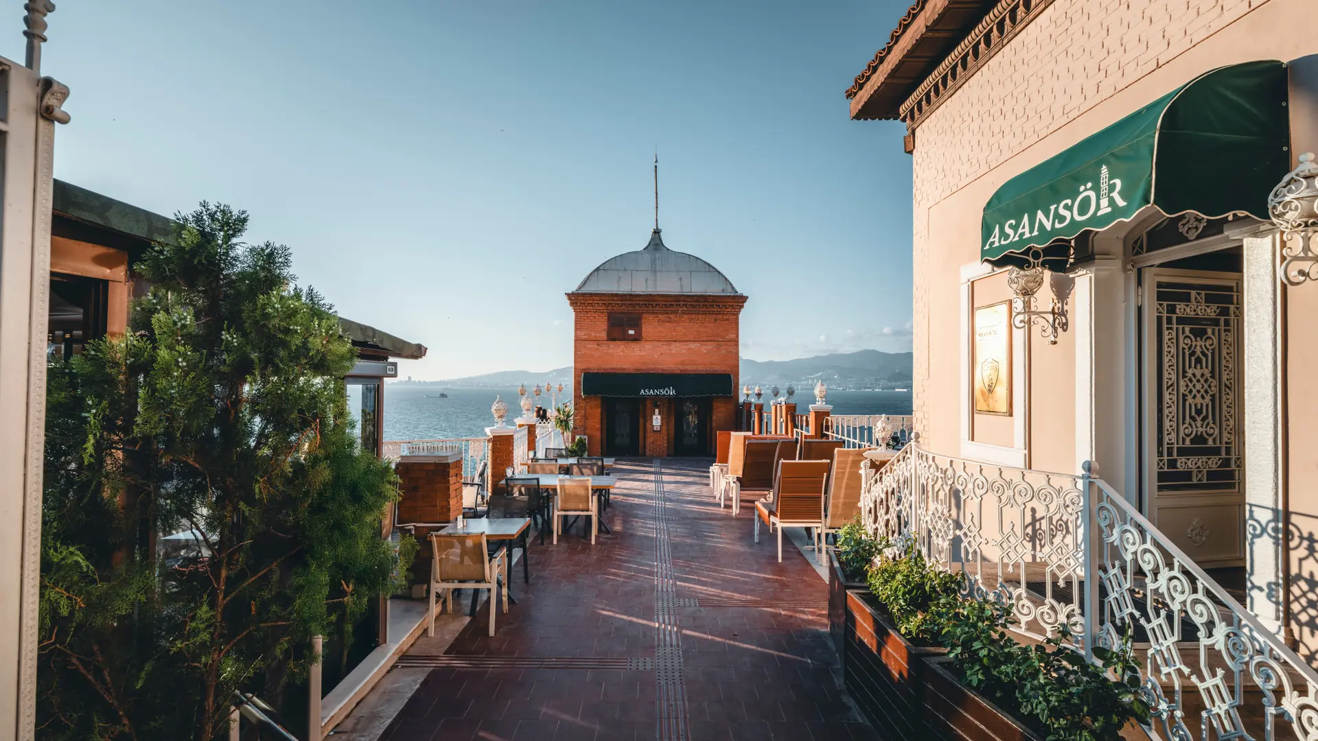 Sunlit historical Asansör terrace above İzmir Bay, shown as a wider city scene