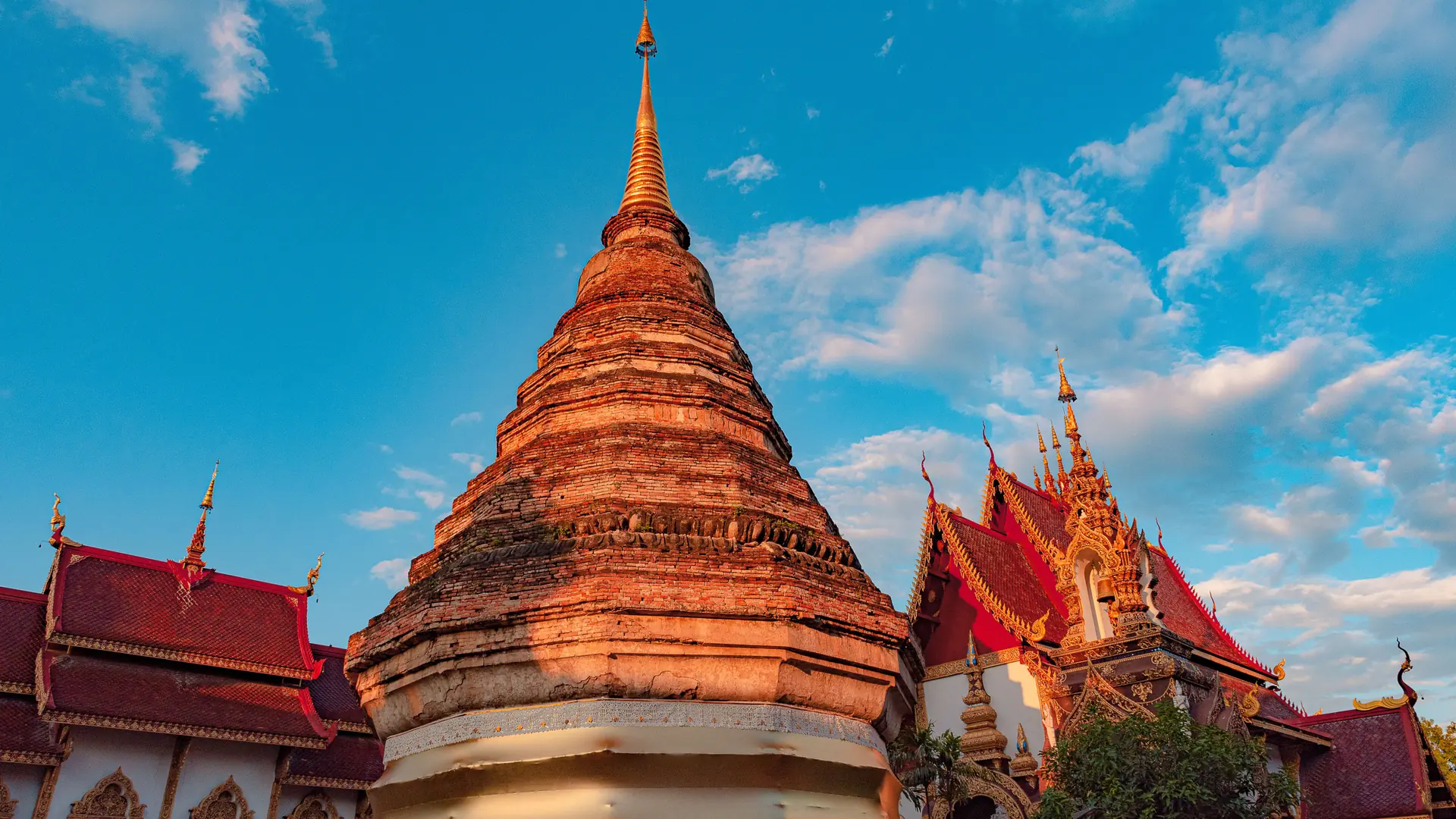 Sunlit brick chedi and temple roofs inside Chiang Mai's Old City