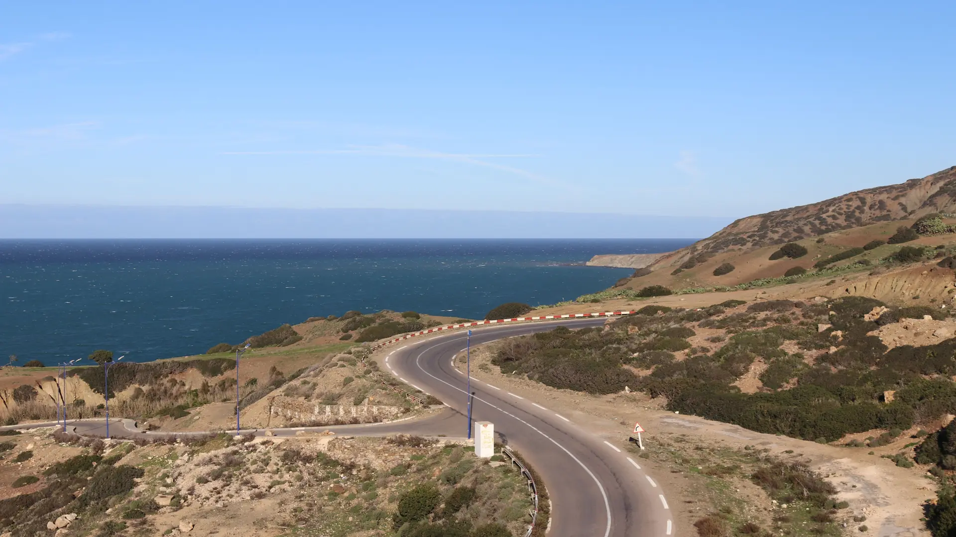 a winding coastal road above deep blue Atlantic water under a clear sky