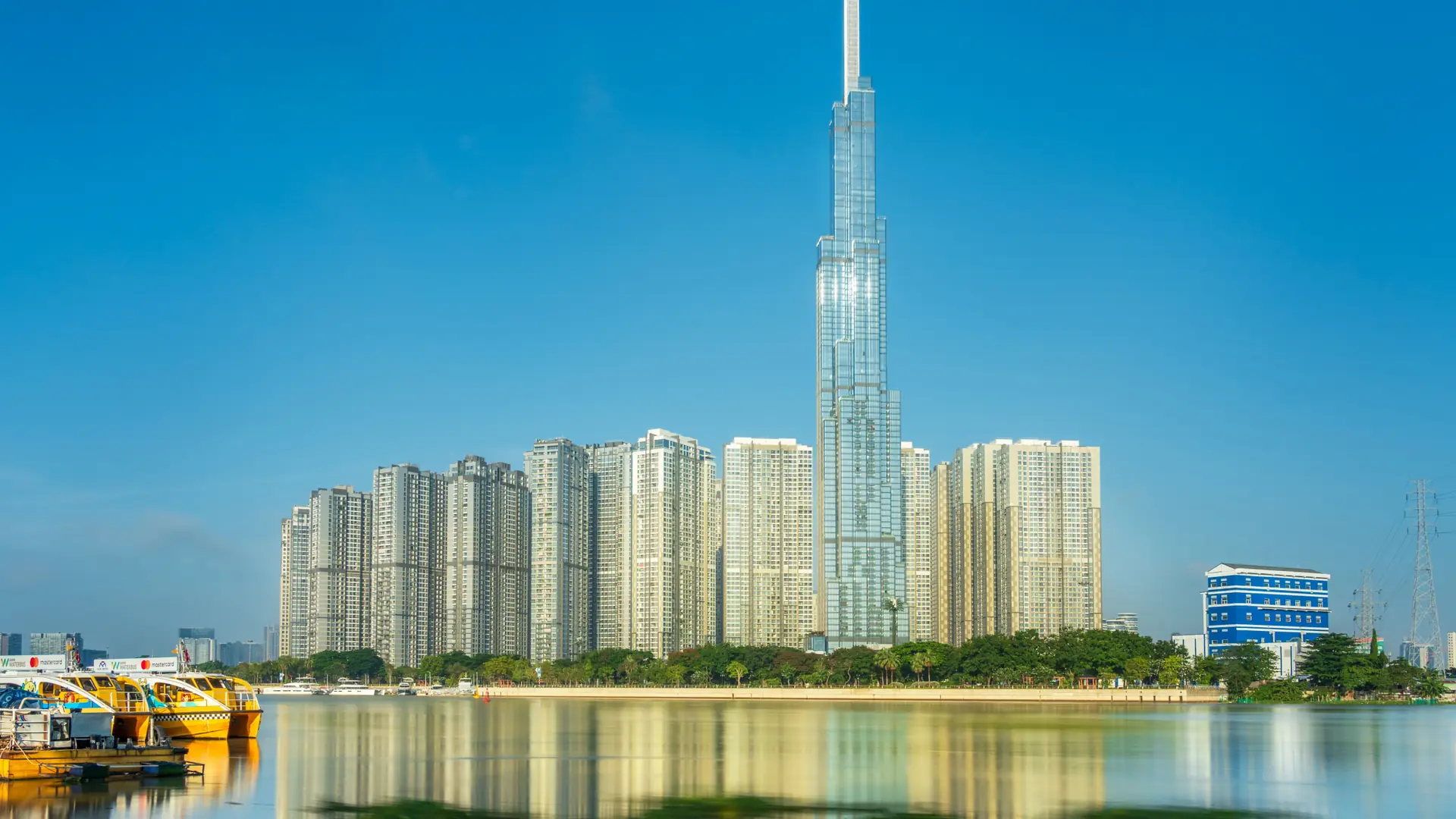 Landmark 81 reflected in the Saigon River under blue skies, a wider city scene