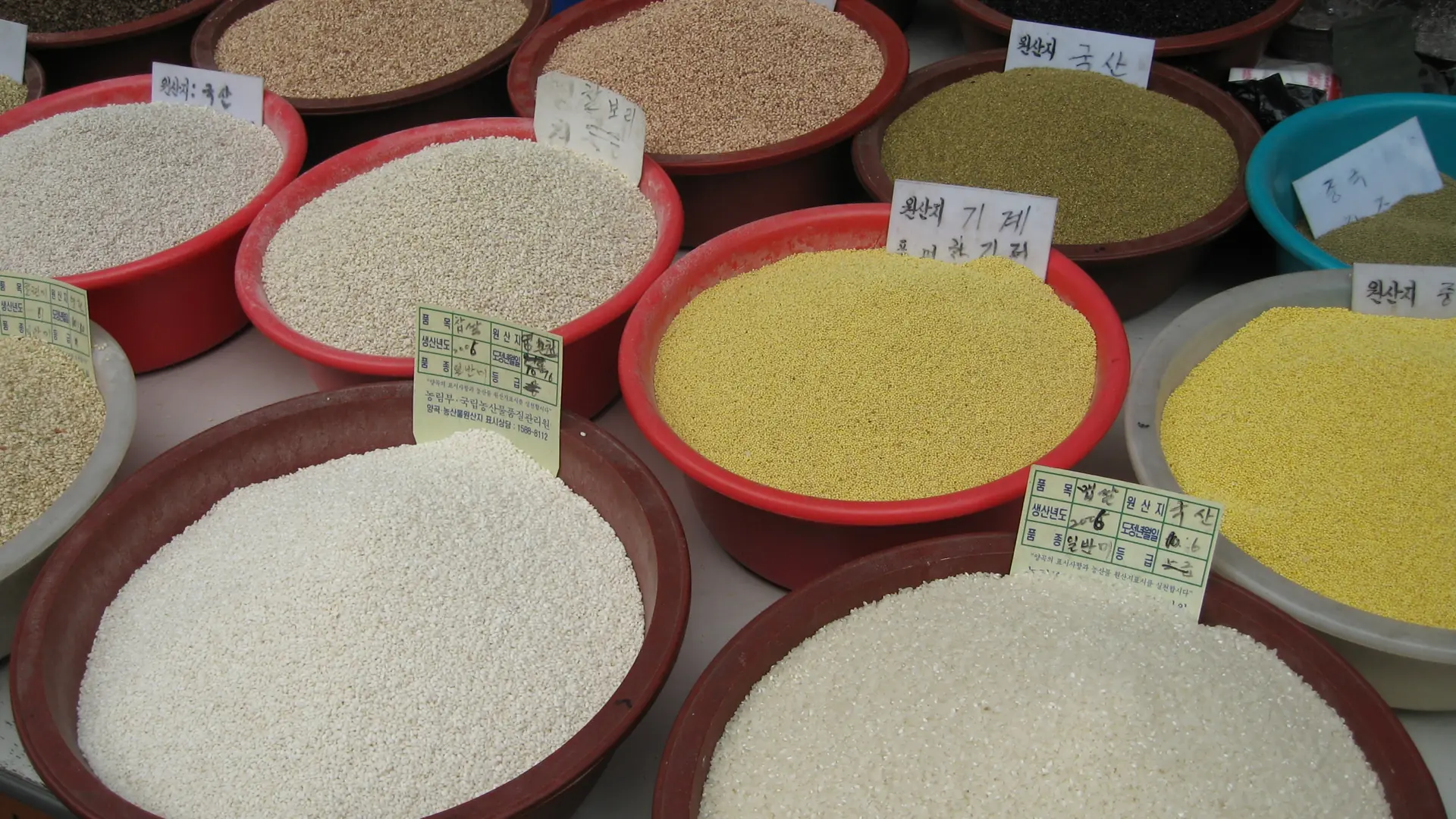 Sacks of grain and rice on display at a covered Korean market stall, typical of Jukdo Market's produce and dry-goods sections