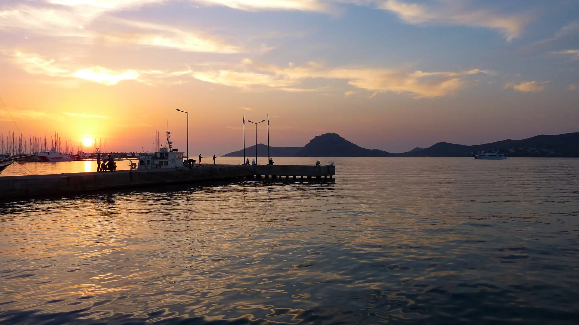 Yalıkavak waterfront and moored boats silhouetted against a warm Aegean sunset