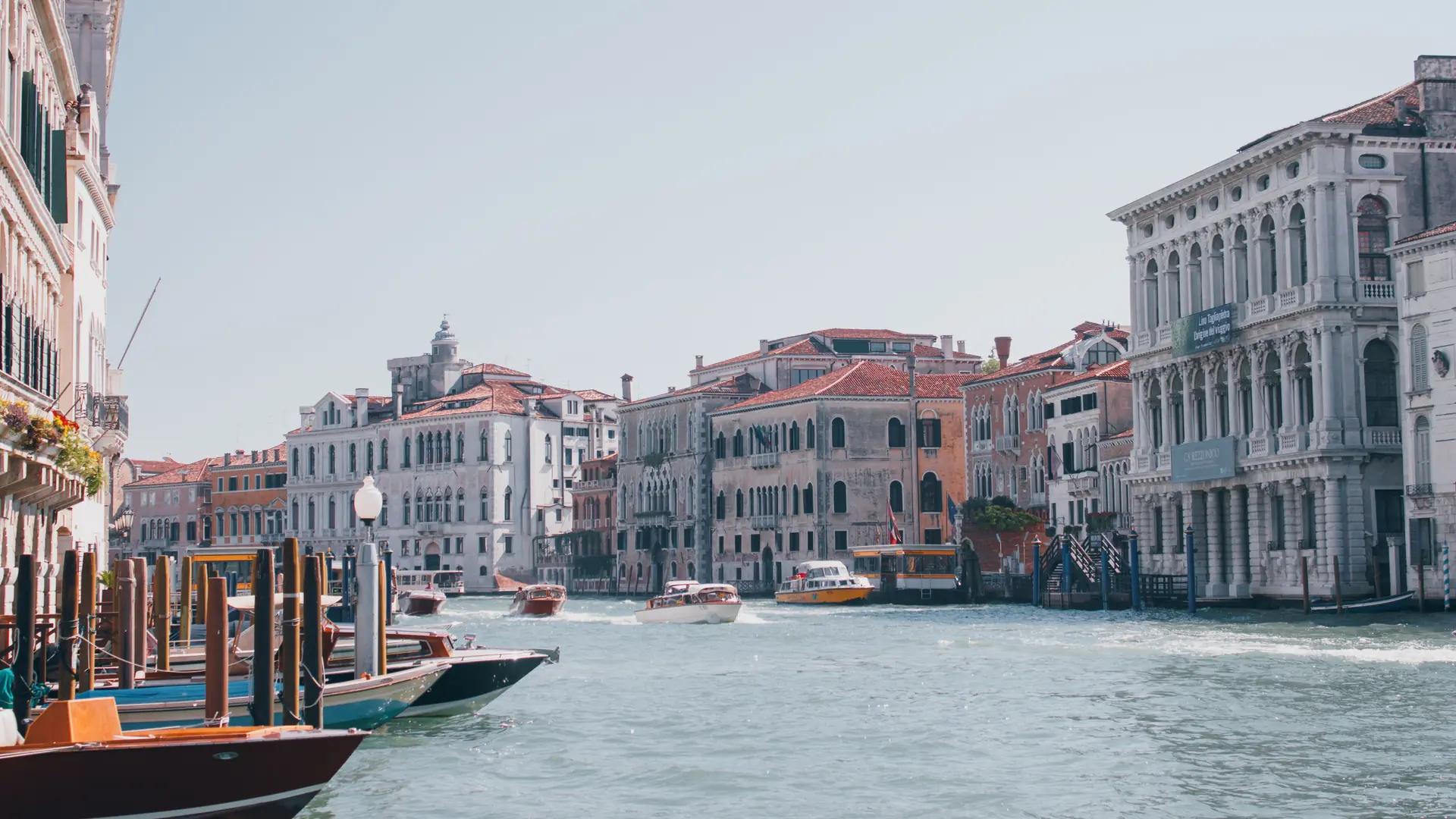 a sunlit stretch of Venice's Grand Canal with a vaporetto and historic façades