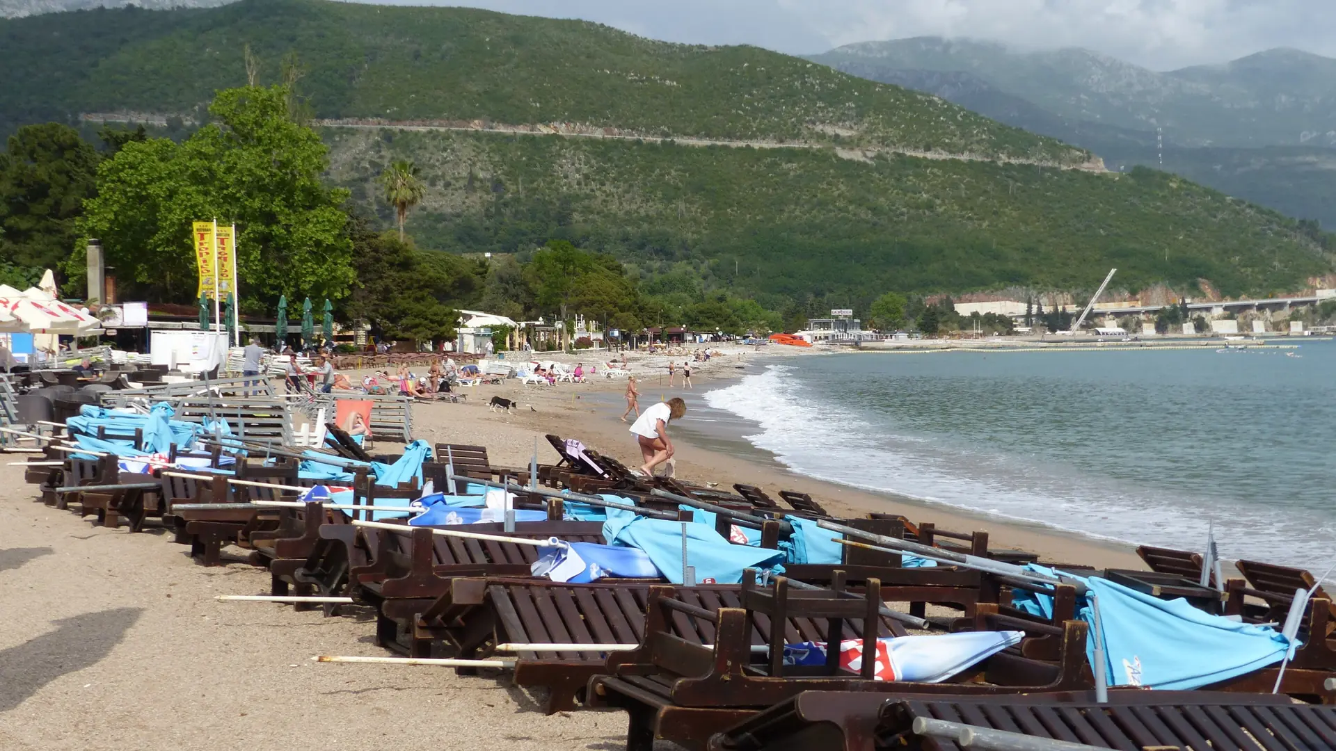 Sun loungers line Slovenska Beach, with Budva Bay and green hills behind