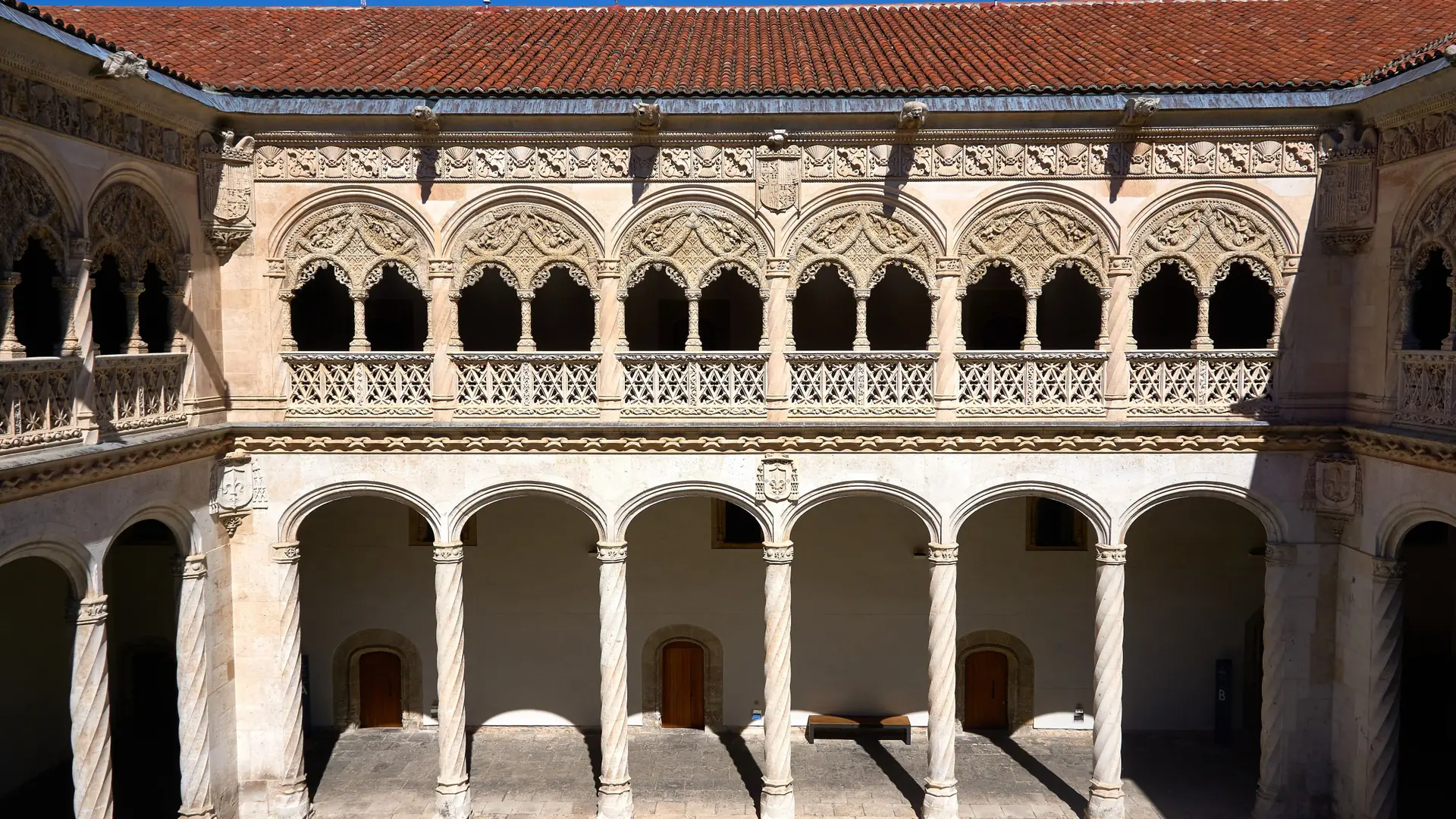 Sunlit University of Coimbra courtyard with carved stone arches and columns