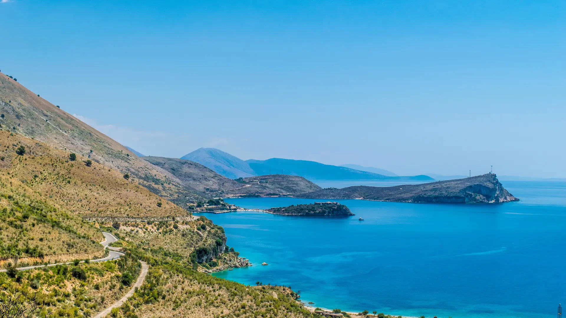 The Porto Palermo headland and turquoise bay on the Albanian Riviera south of Himarë on a bright day