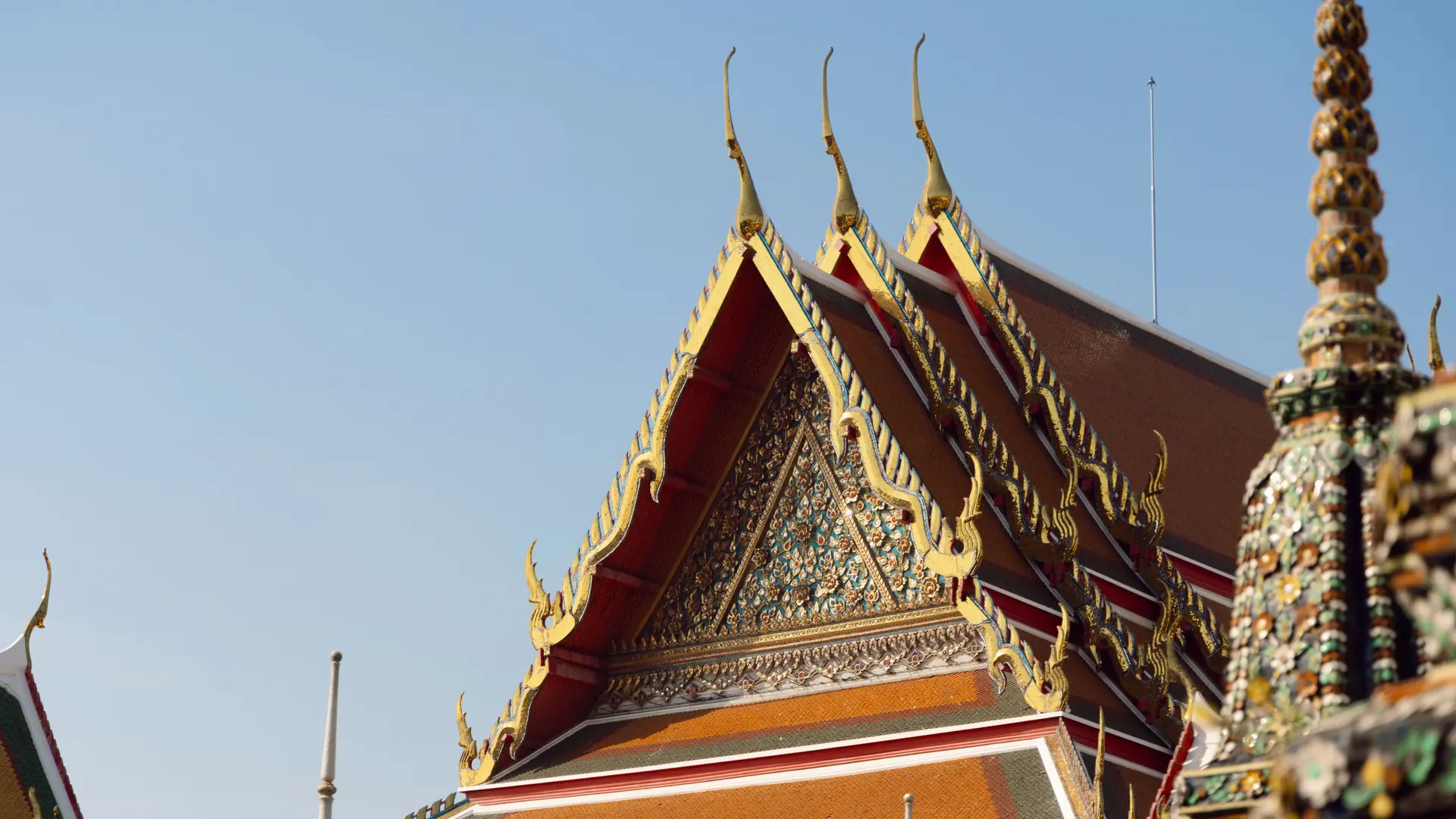 Wat Pho's layered temple roofs and glazed tiles beneath a clear Bangkok sky