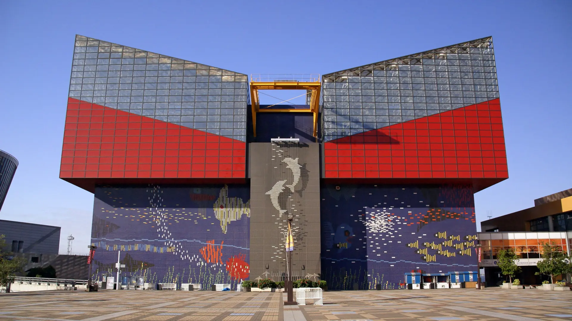 Kaiyukan’s red and blue aquarium facade and sunlit entrance plaza in Osaka’s Tempozan district