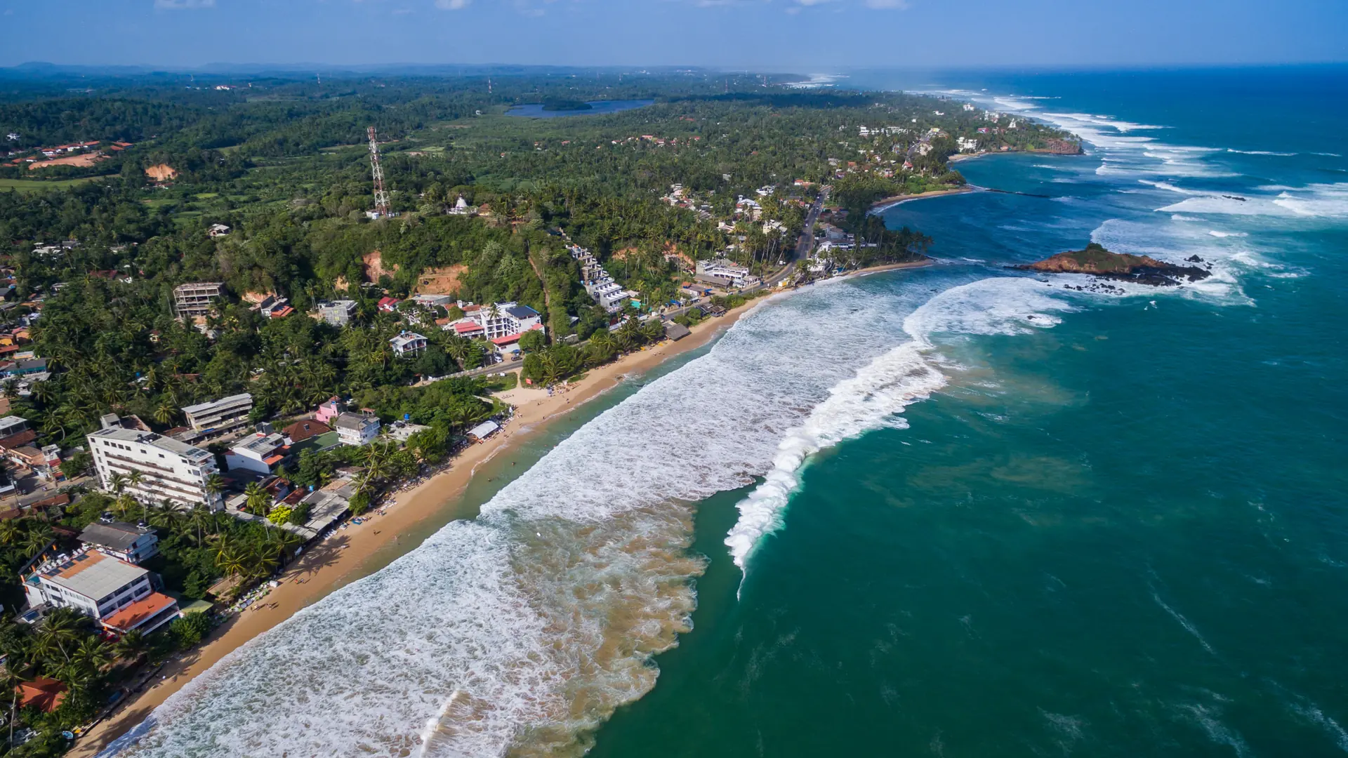 Aerial view of Mirissa's curved shore and turquoise surf