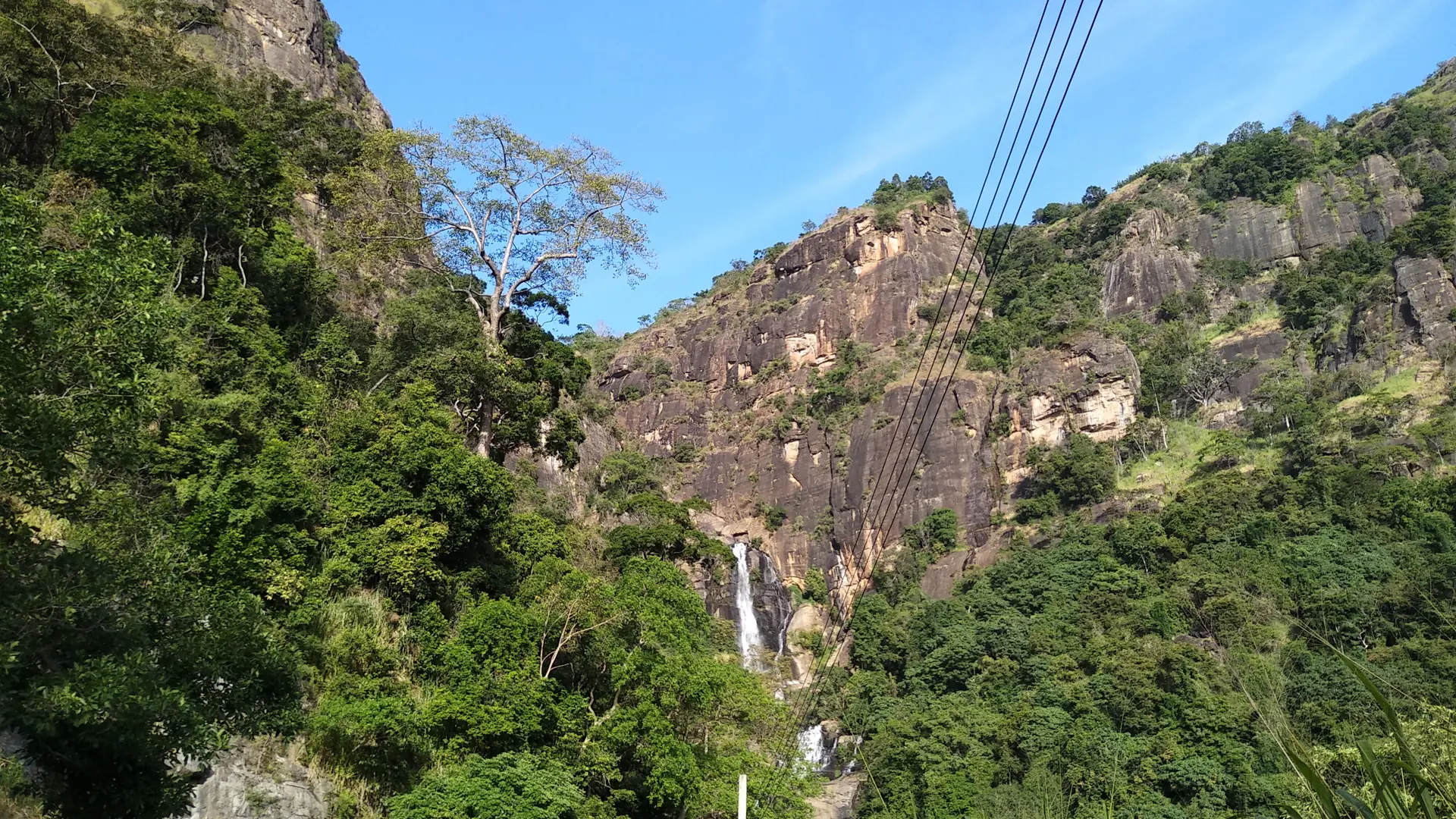 Rocky slopes and Rawana Falls outside Ella beneath a blue sky