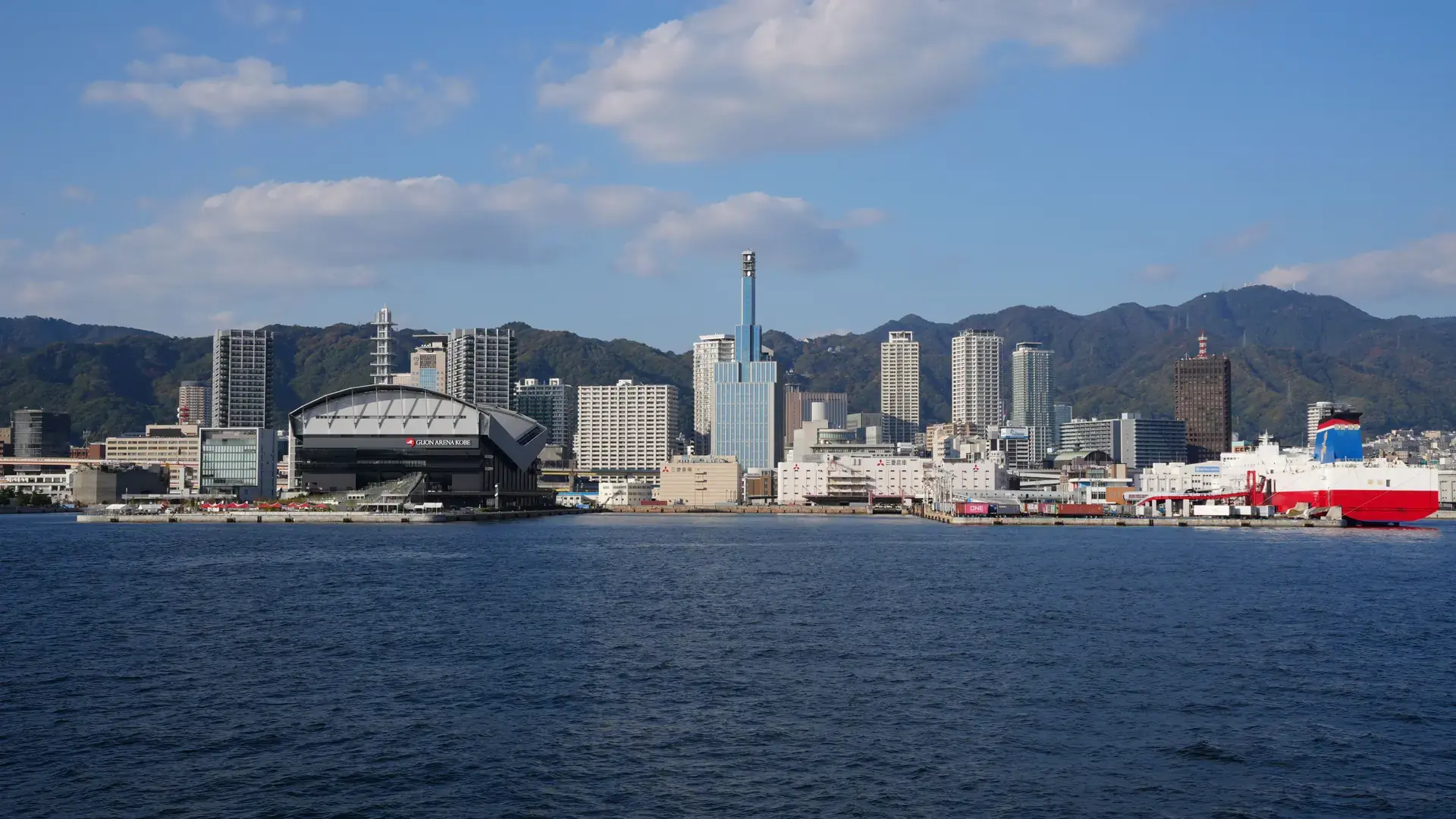 Kobe's bright coastal skyline and green Rokko Mountains beneath a clear blue sky