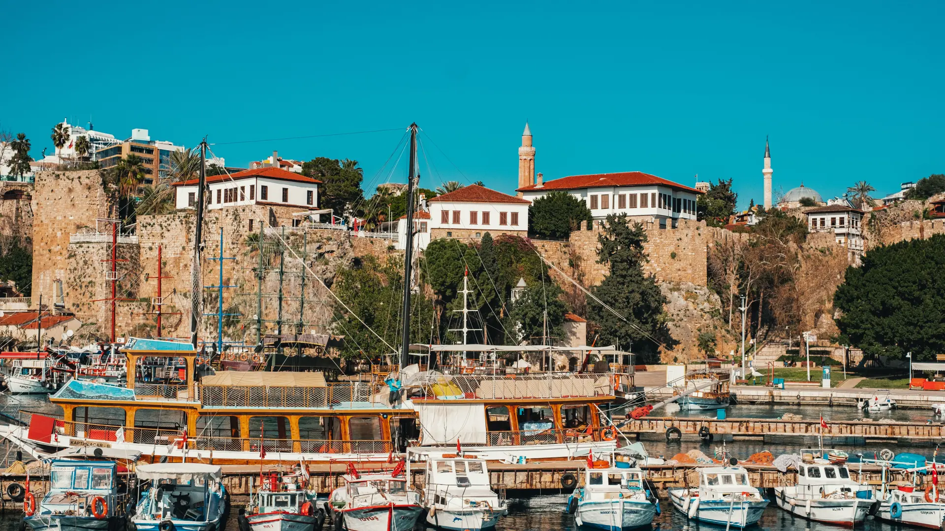 Boats and an ancient stone tower in Antalya old harbour