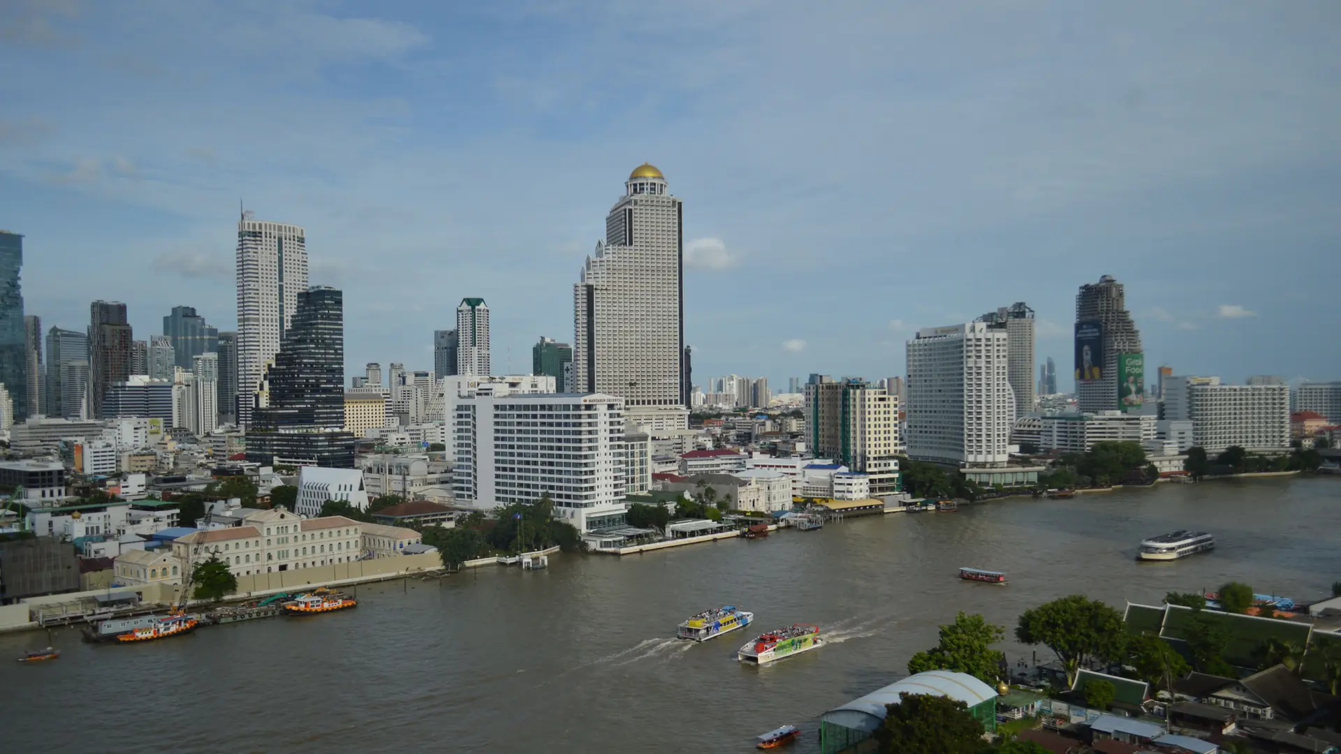 Boats crossing the Chao Phraya below Bangkok's modern riverside skyline