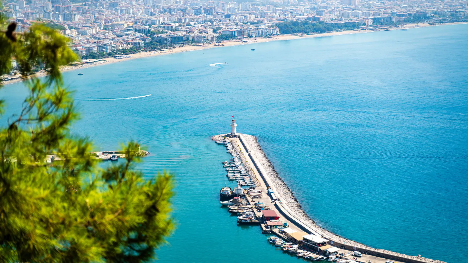 Alanya bay and harbour lighthouse in sunshine, shown as a wider city coastal scene for Oba