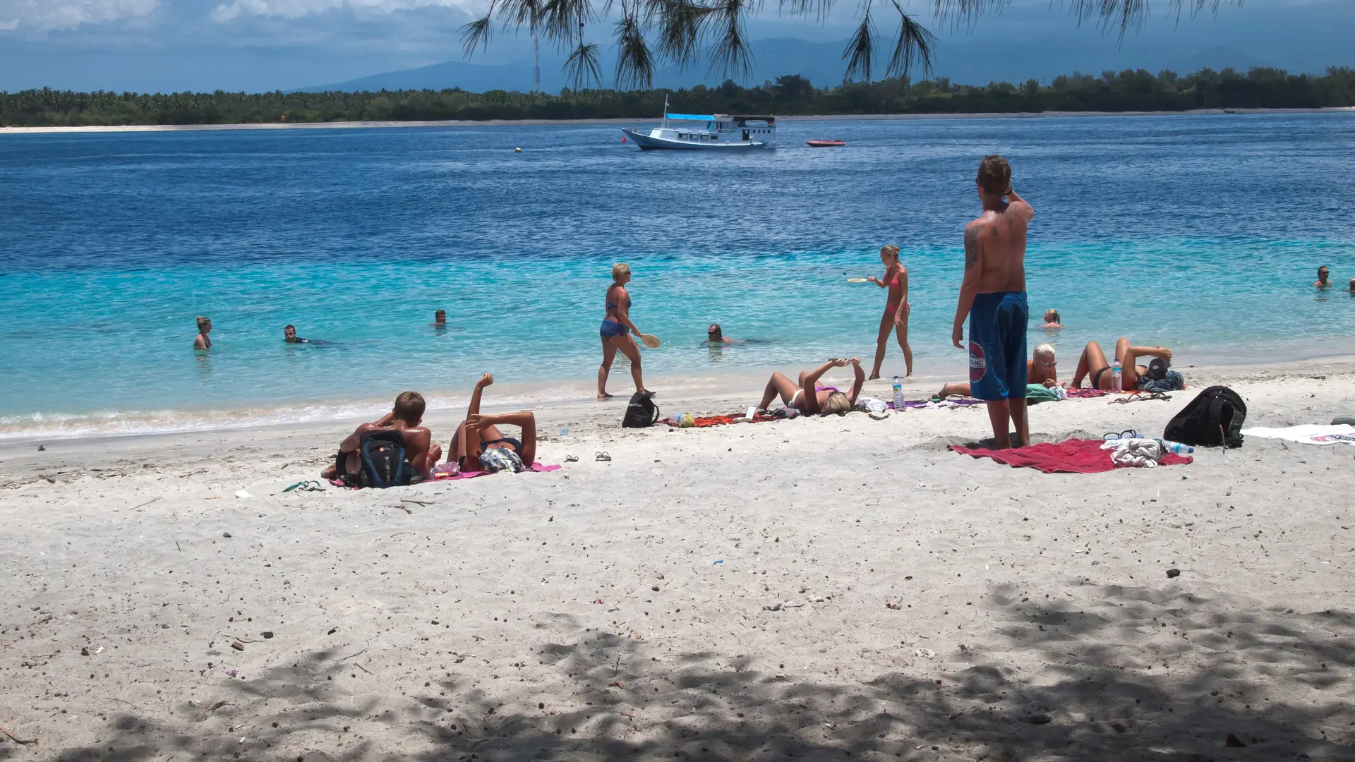 Visitors relaxing and playing beside turquoise water on a wider Gili Trawangan beach