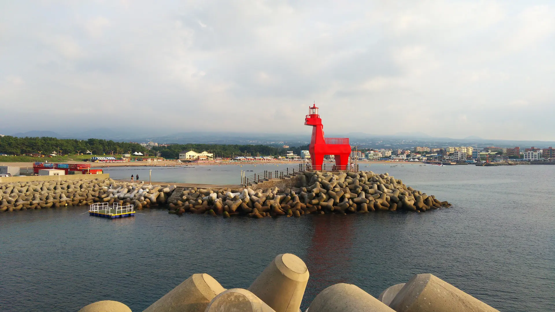 A red horse-shaped lighthouse beside the harbour and waterfront in Jeju City