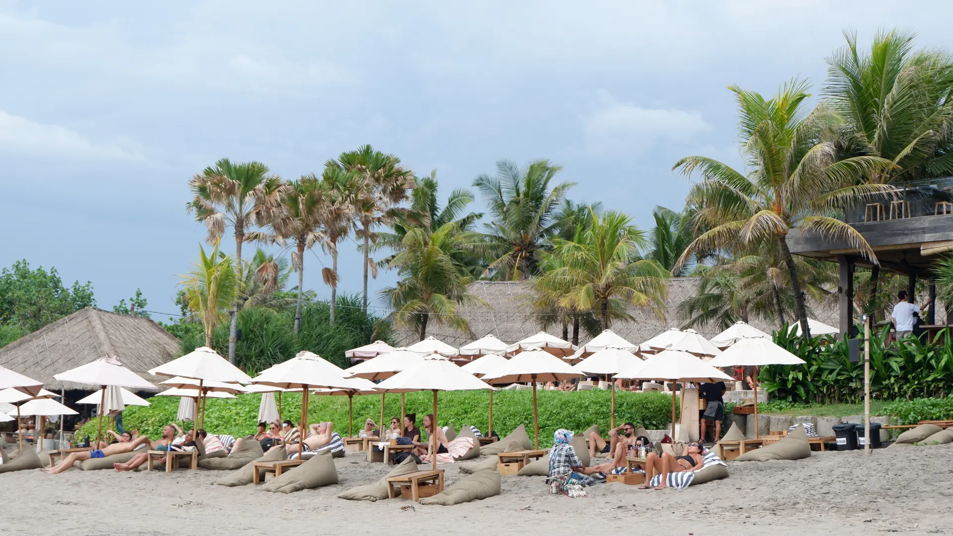 White umbrellas, loungers and thatched roofs beside a Canggu beach
