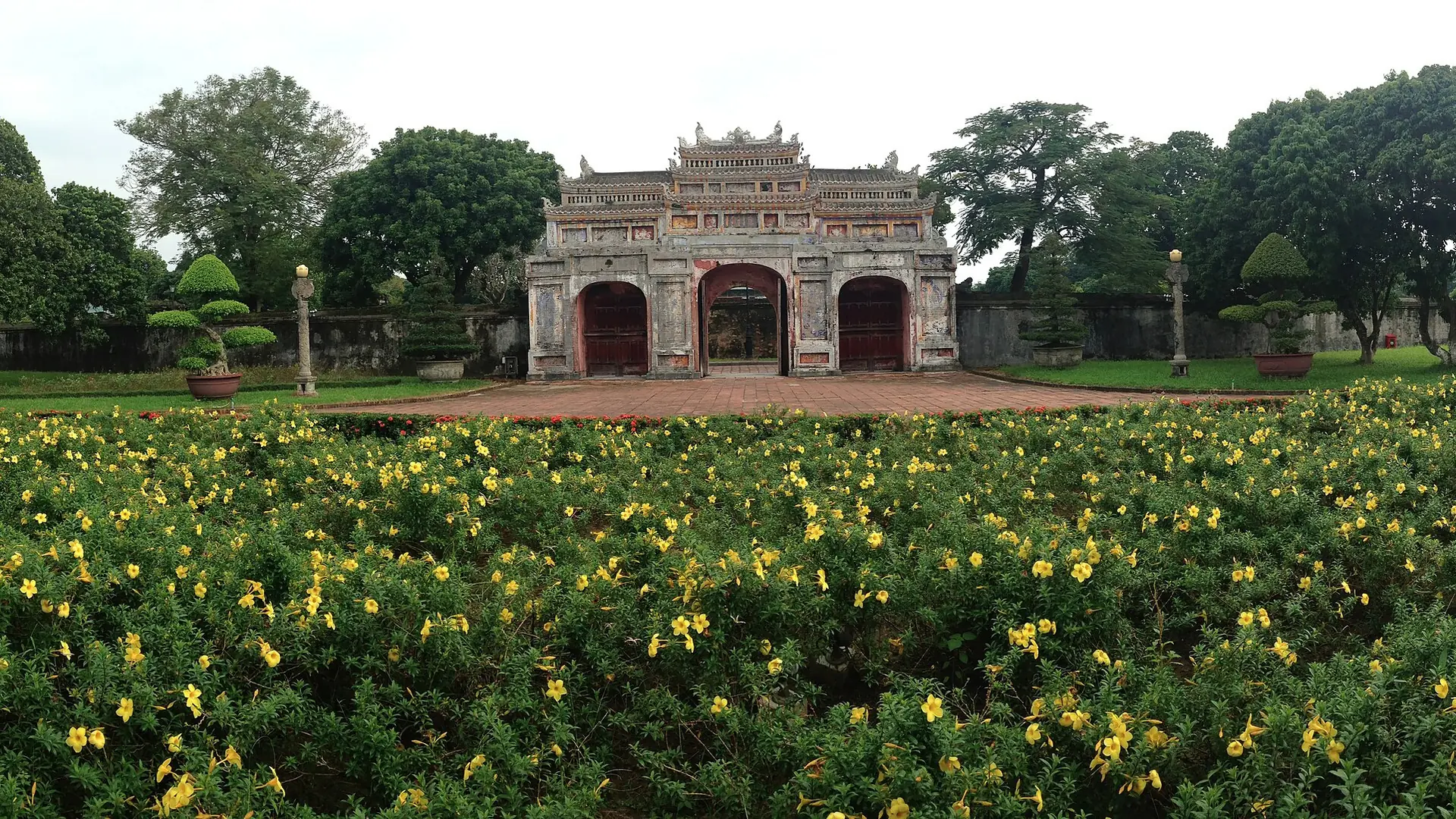 A flower-filled courtyard looking from Dien Tho Palace toward Phung Tien Palace inside Hue Imperial City