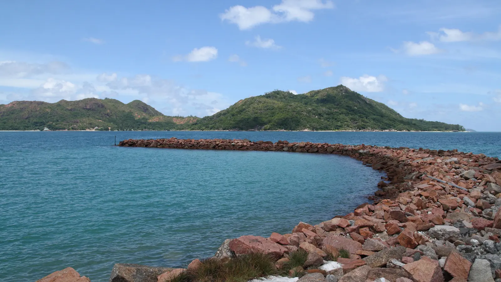 Stone breakwater and blue water in Baie Sainte Anne on Praslin