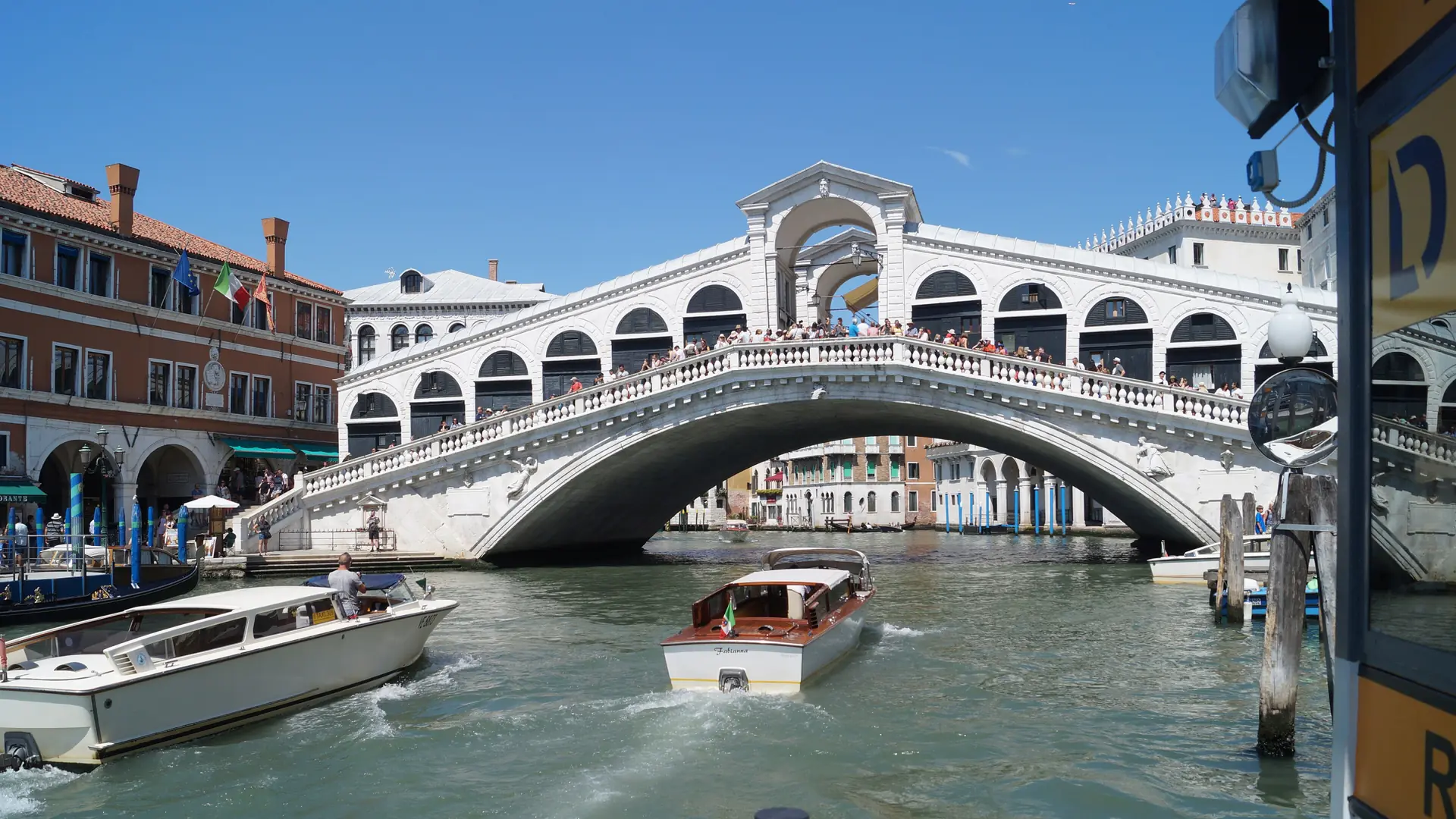 Rialto Bridge spanning Venice’s Grand Canal under a bright blue sky.