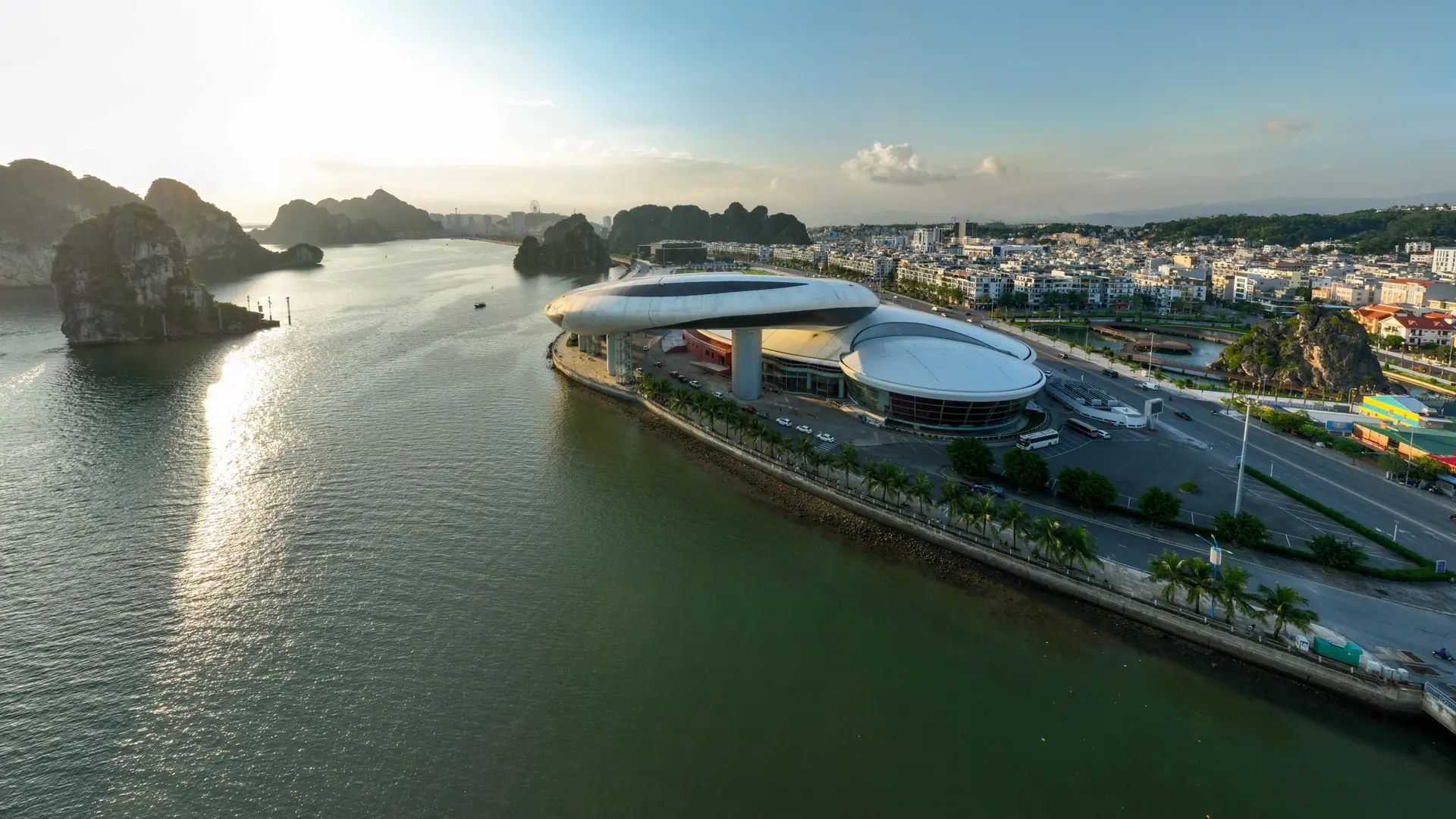 Sunlit Hon Gai waterfront with the dolphin-shaped Quang Ninh exhibition centre beside the bay