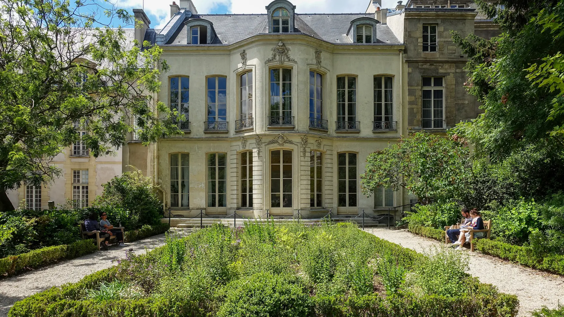 A sunlit mansion facade and planted garden in the Marais, Paris