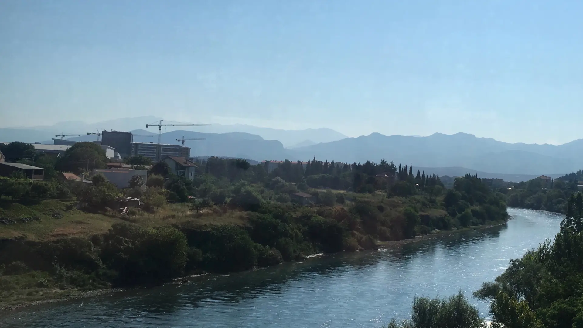 Morača River, tree-lined banks and distant Podgorica hills in daylight