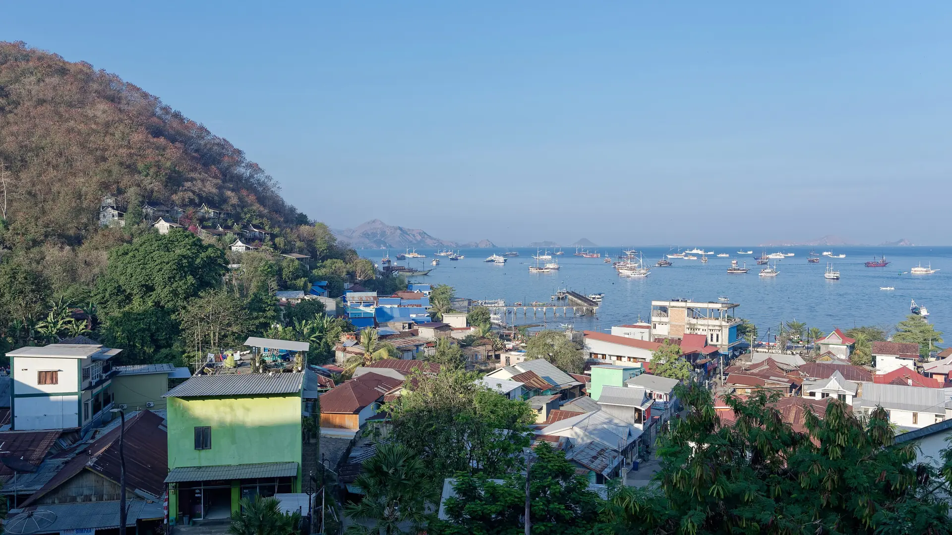 Labuan Bajo’s rooftops and boats beside the sunlit bay