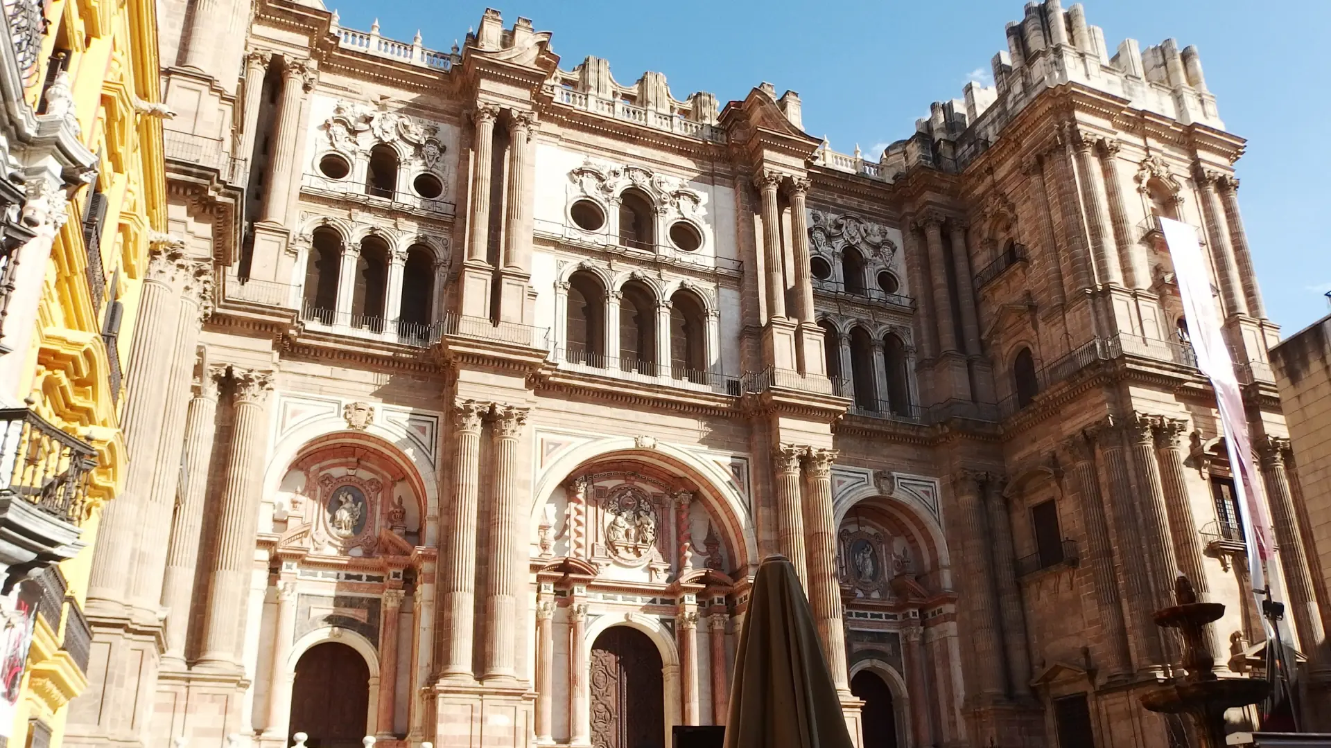 Sunlit portals and ornate main façade of Málaga Cathedral